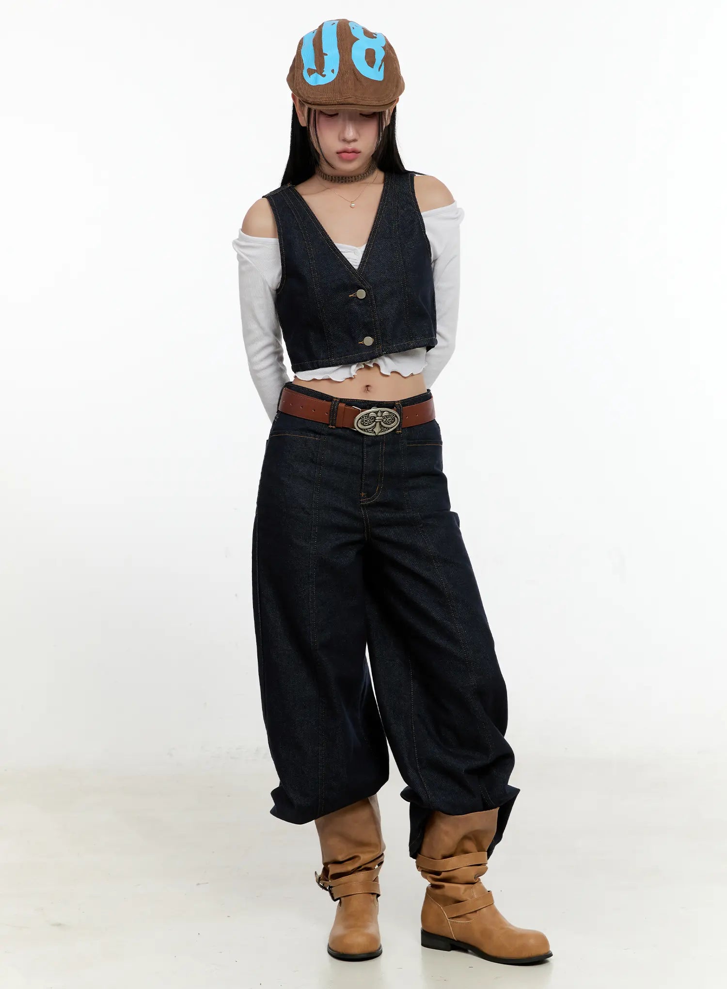 Nala Wide-Leg Bootcut Jeans CN506 in dark blue, full-body editorial shot on model with printed cap, denim vest, brown belt, and tan boots, acubi casual styling.