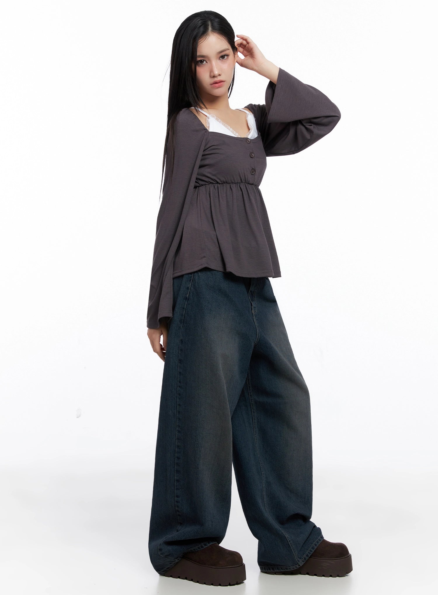 Adelyn Washed Baggy Jeans IS525 in dark blue, side full-body shot on model with hand raised, extra-wide washed denim leg pooling at hem, styled with charcoal peplum top and brown platforms.