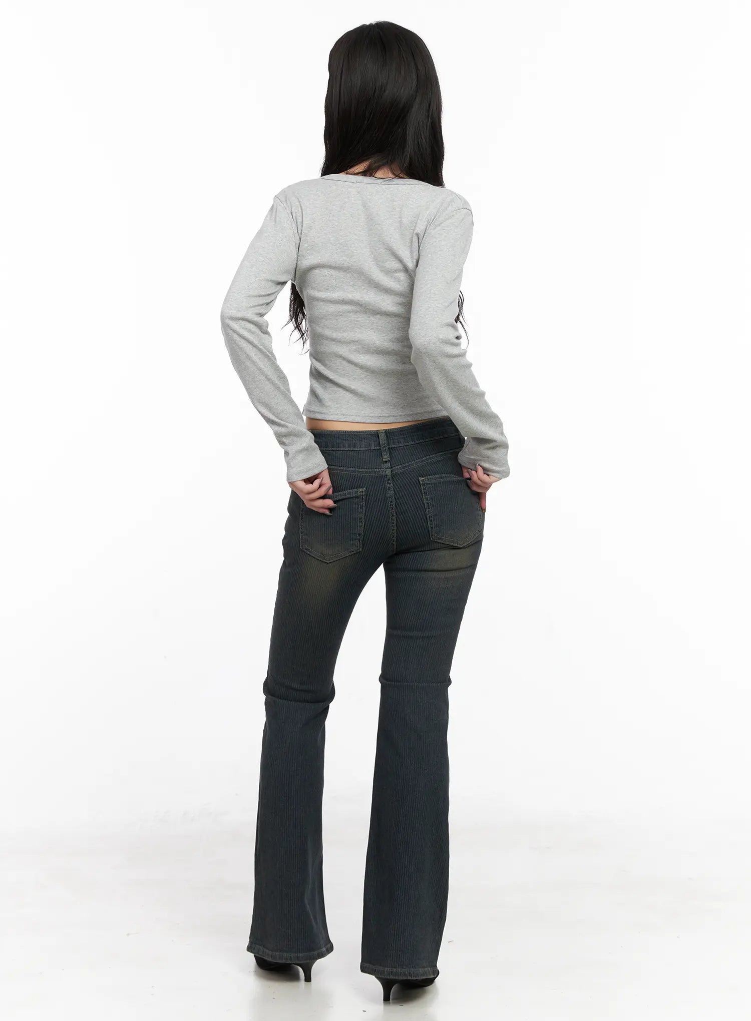 Soleil Hip Pad Stripe Hip Pad Flared Jeans CN512 in dark blue, back full-length shot on model, washed stripe bootcut highlighting hip pad silhouette, back pockets and flared hem, with gray crop top and black stiletto mules.