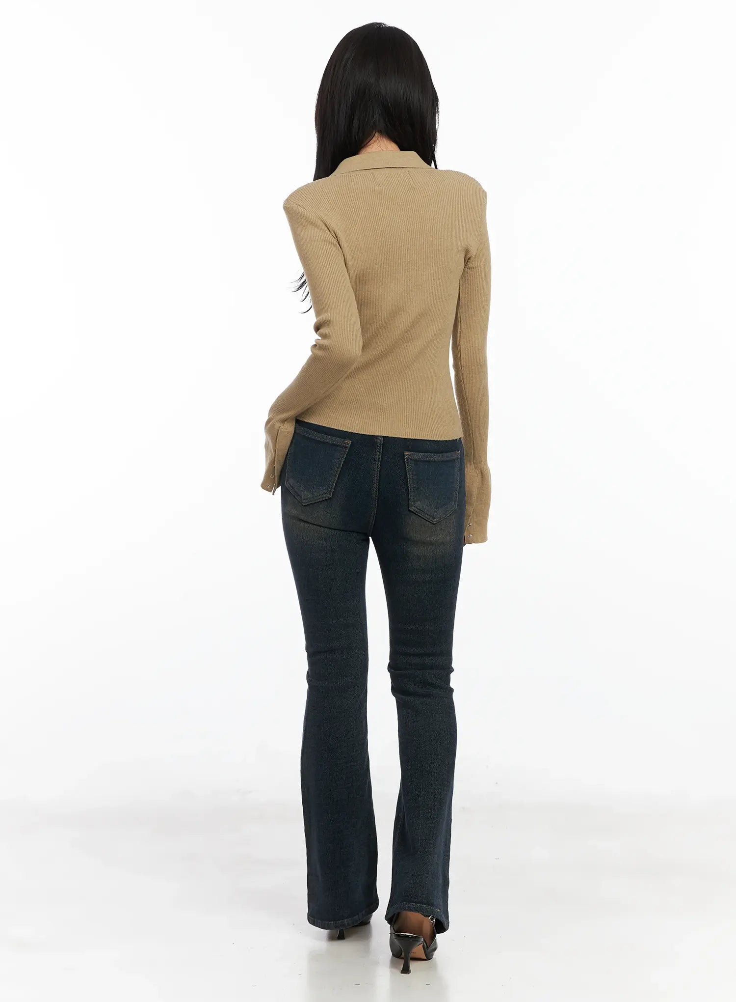 Jordyn High-Waist Bootcut Jeans CD502 in dark washed indigo, full-length back view on model, back patch pockets visible, long bootcut silhouette, paired with camel ribbed top and black heels.