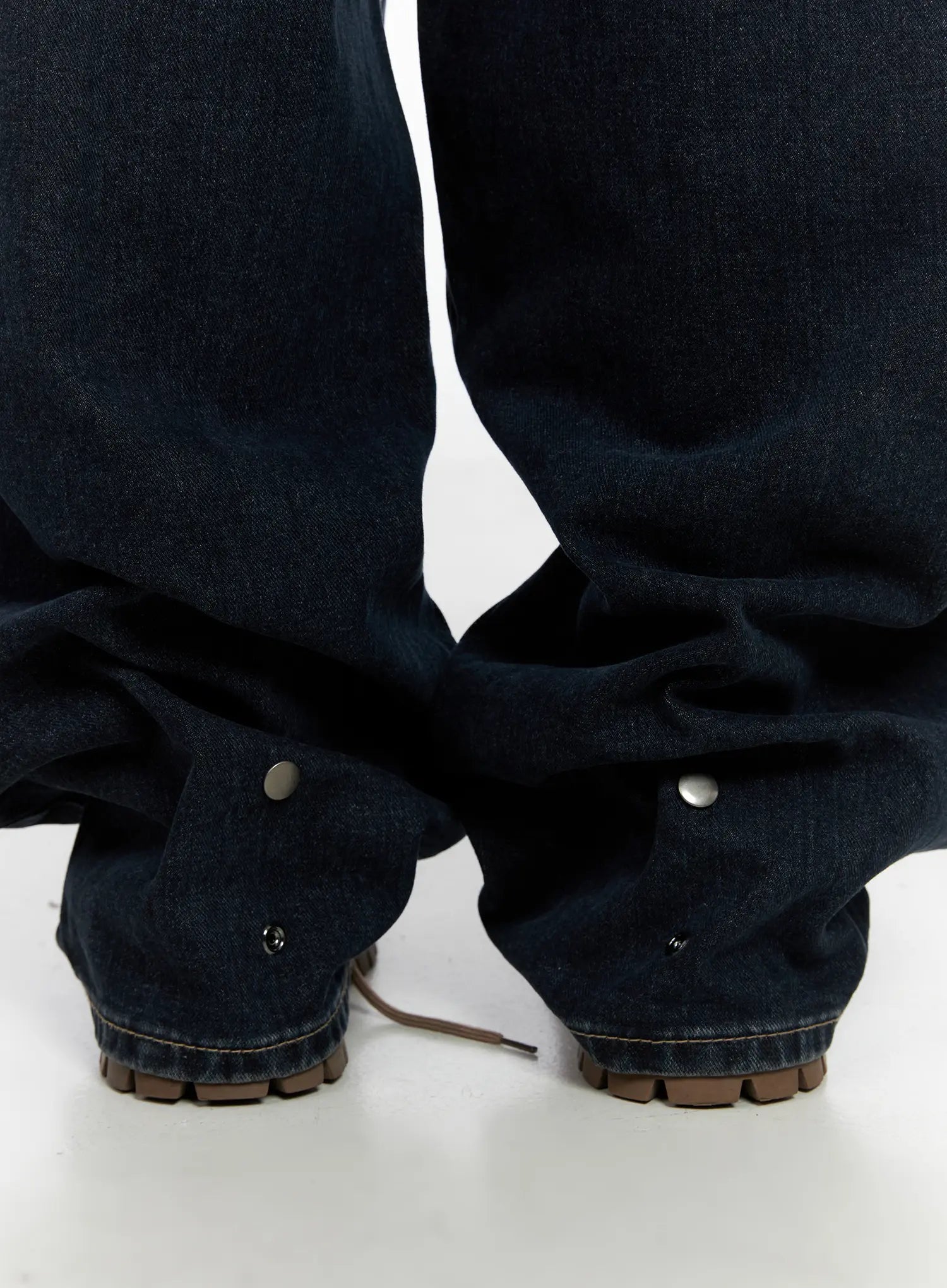 Isla Washed Baggy Jeans CO521 in dark blue, macro close-up of hem and ankle area, heavy cotton fabric drape with metal snap detail at cuff pooling over lug-sole boots.