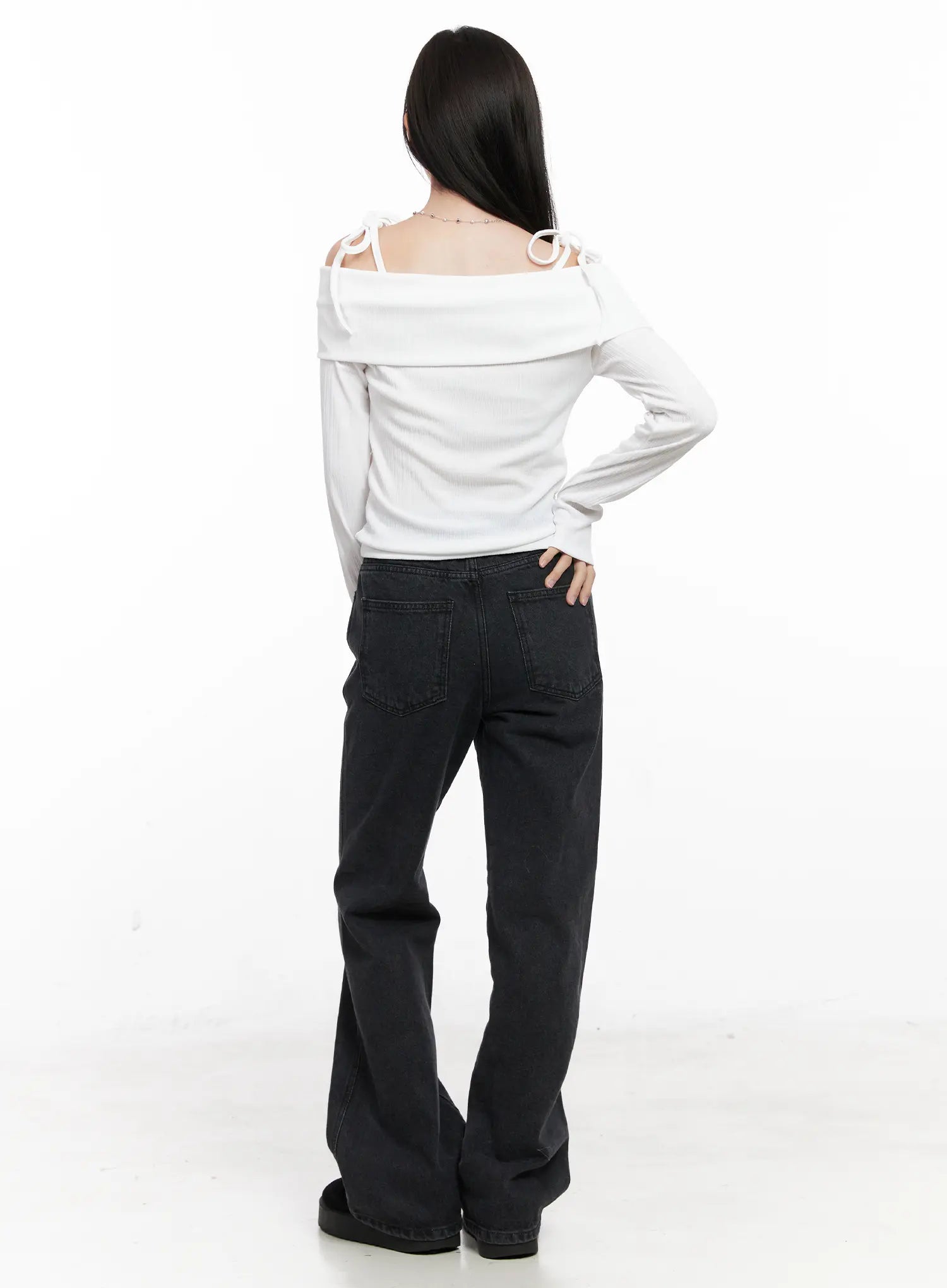 Eileen Belted Flare Jeans CN504 in washed black, full-length back view on model, loose flare leg pooling at hem, back pocket details, styled with white off-shoulder top.
