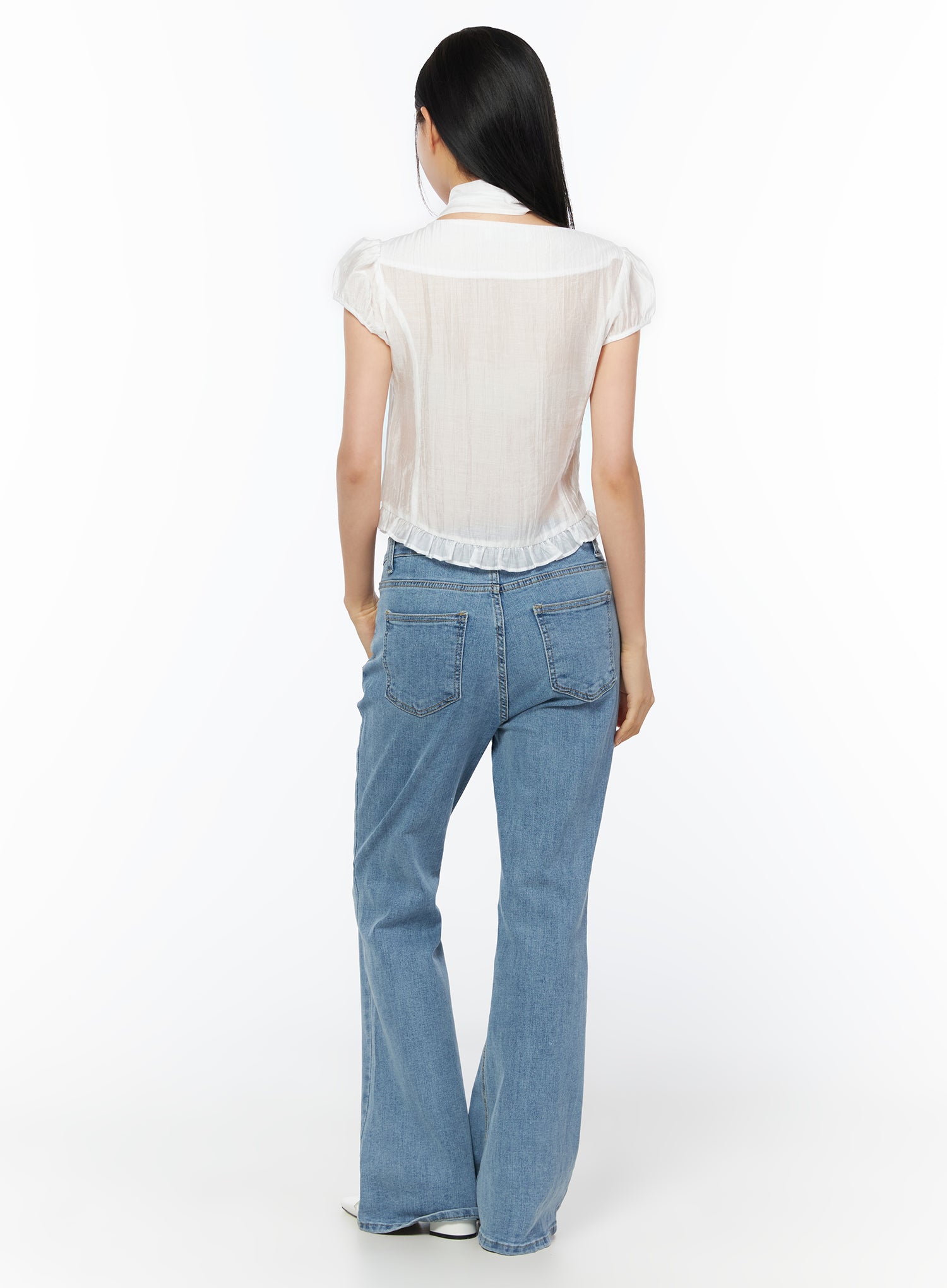 Puff Sleeve Shirred Blouse with Scarf IU519 in white, back view on model, showing sheer fabric, subtle shirring texture, ruffled hem and scarf at neckline, with blue flare jeans.
