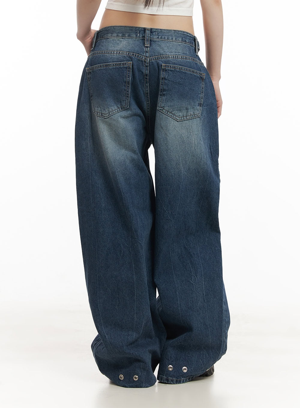 Bri Oversized Buttoned Baggy Jeans CF518 in dark blue, back view on model, dual back pockets with washed fading, voluminous baggy leg, snap button hem detail, white crop top.