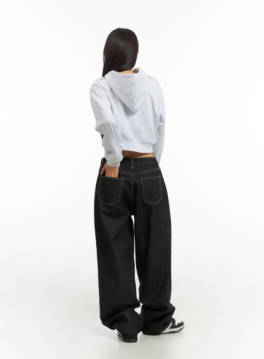 Clover Stitched Baggy Jeans IS402 in black, full back view on model, rear patch pockets with contrast stitching, oversized baggy leg, paired with grey crop hoodie and white sneakers.