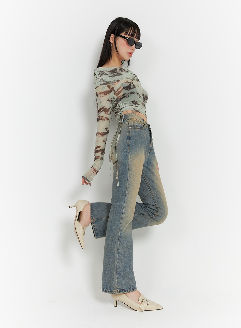Washed Flared Jeans IF426 in blue, side full-length view on model in dynamic pose, slim flared leg with sandy washed fade, paired with printed mesh top and cream heels.