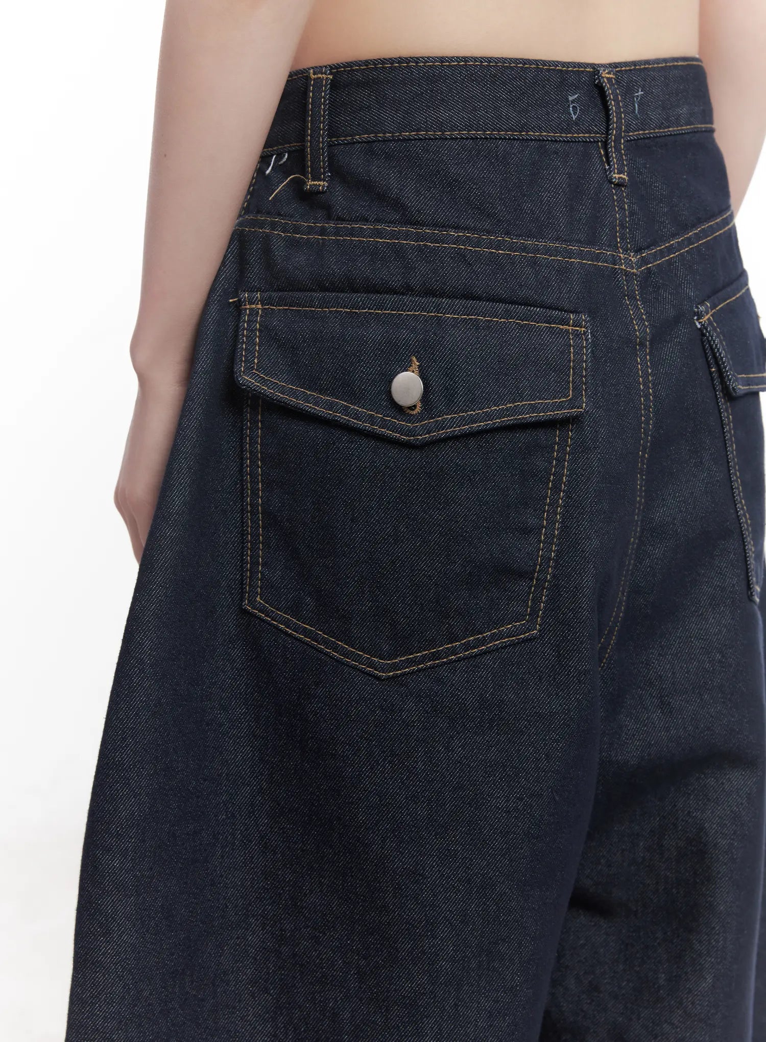 Hyein No-Fade Relaxed-Fit Jeans CU519 in dark blue, close-up detail of back flap pocket with snap button and golden contrast topstitching on raw indigo cotton denim.