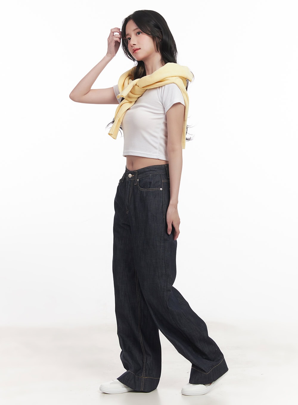 Seline Non-Fade Wide-Leg Jeans CA510 in dark blue, side editorial view on model, wide-leg denim with contrast stitching, styled with white crop tee and yellow cardigan tied around shoulders.
