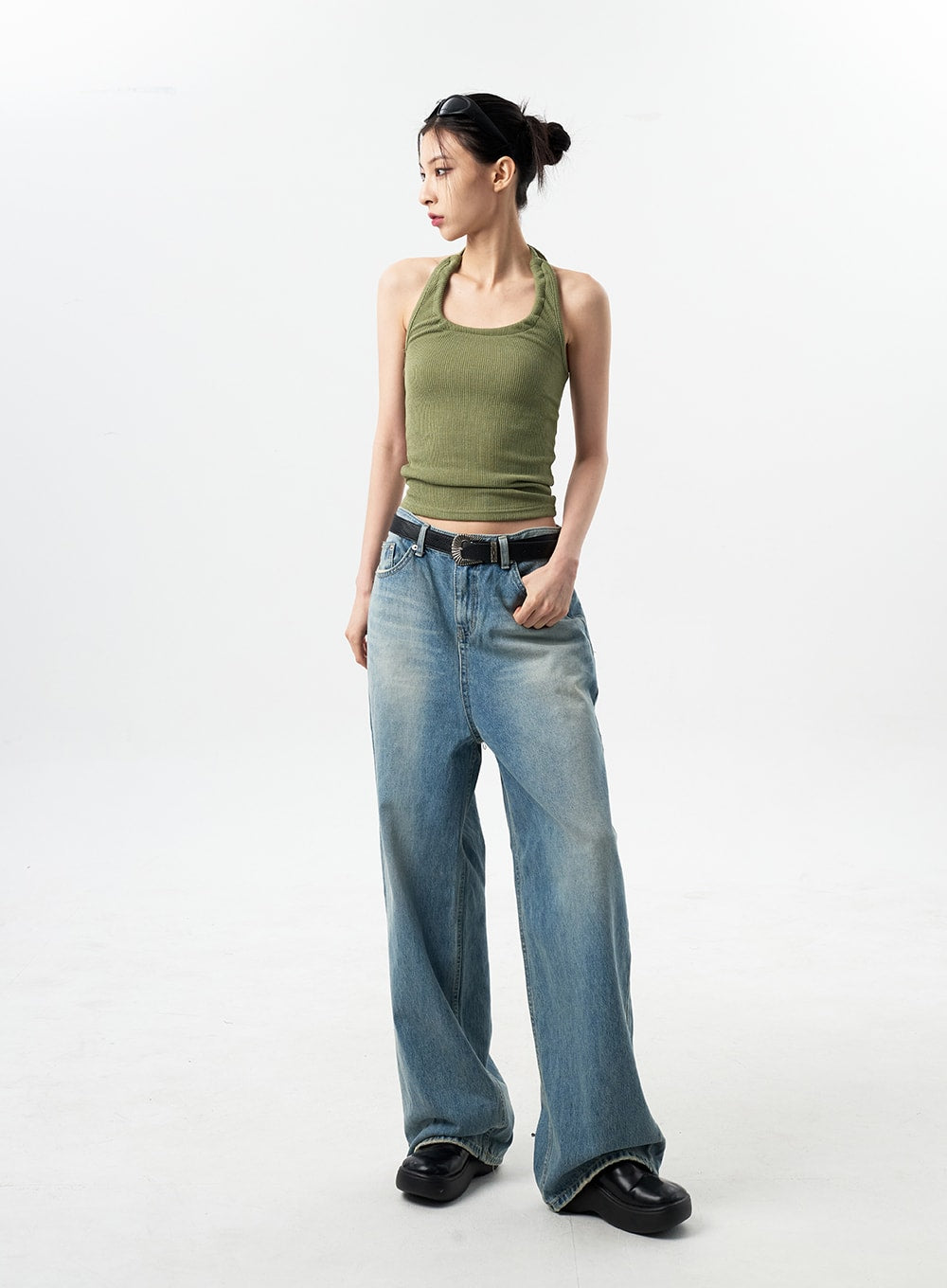Oversized Jeans Unisex CY312 in washed blue, full-length side view on model looking away, wide-leg denim draping floor-length, paired with green halter top and belt.