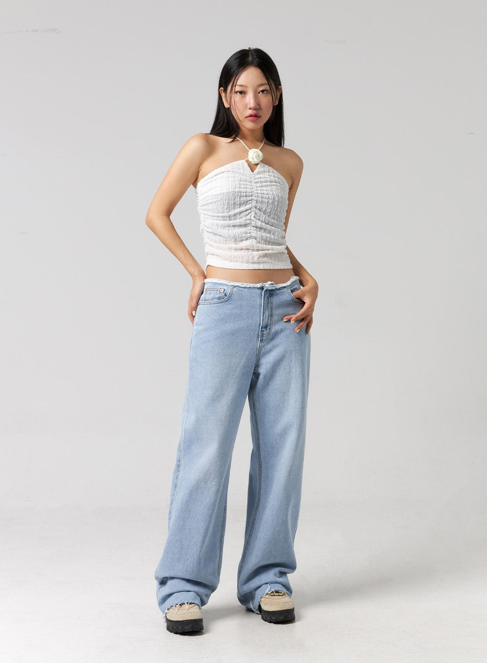Cut Waist Wide Leg Jeans CG323 in light blue, full-body front shot on model, both hands on hips, wide-fit cotton denim with frayed waist, styled with white ruched halter top.