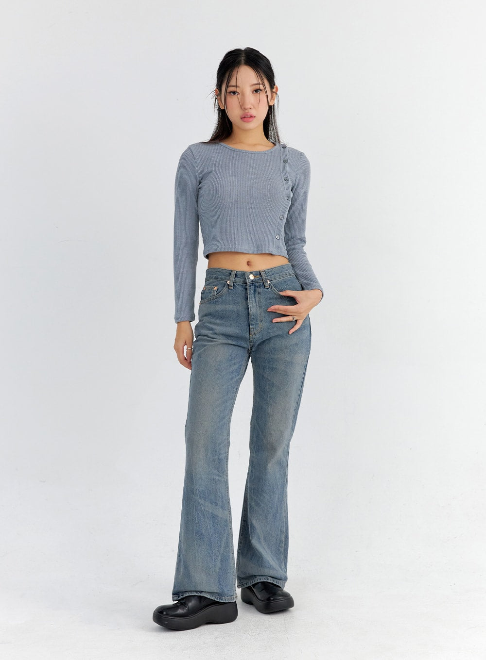 Vintage Washed Bootcut Jeans CO325 in blue, full-body front shot on model facing forward, slim fit washed cotton denim with gentle bootcut flare, styled with blue-grey ribbed crop top and black loafers.