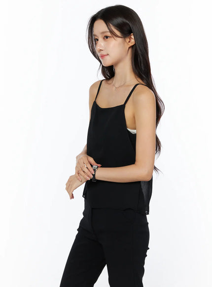 Sheer Ribbon Cami Top CU522 in black, side view on model, square neckline, thin straps, layered sheer hem, inner white lining visible at side, styled with black trousers.
