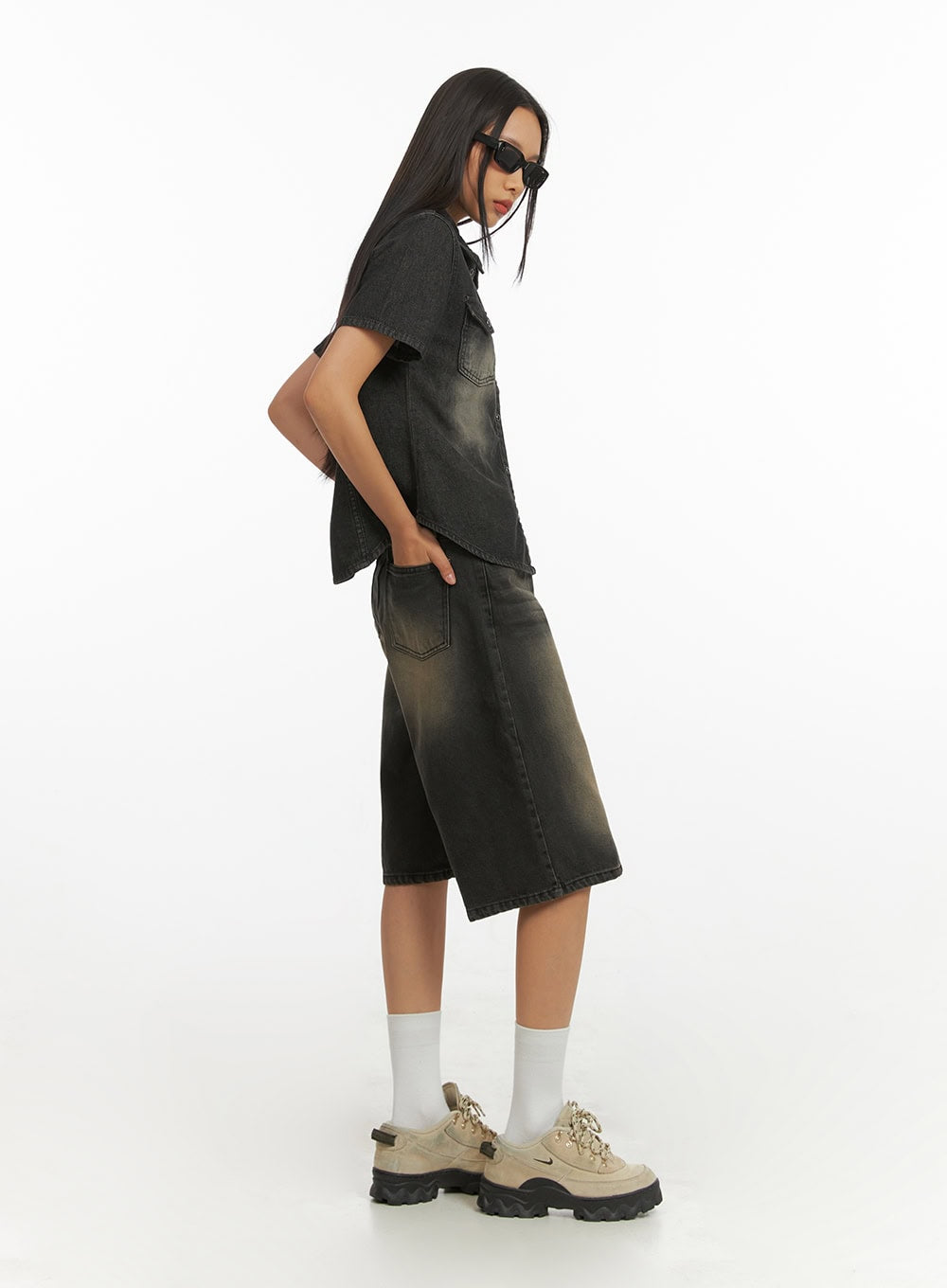 Color Washed Jorts IY422 in black washed denim, side view on model with sunglasses, wide-leg jorts styled in denim-on-denim look with washed short-sleeve shirt, street acubi styling.