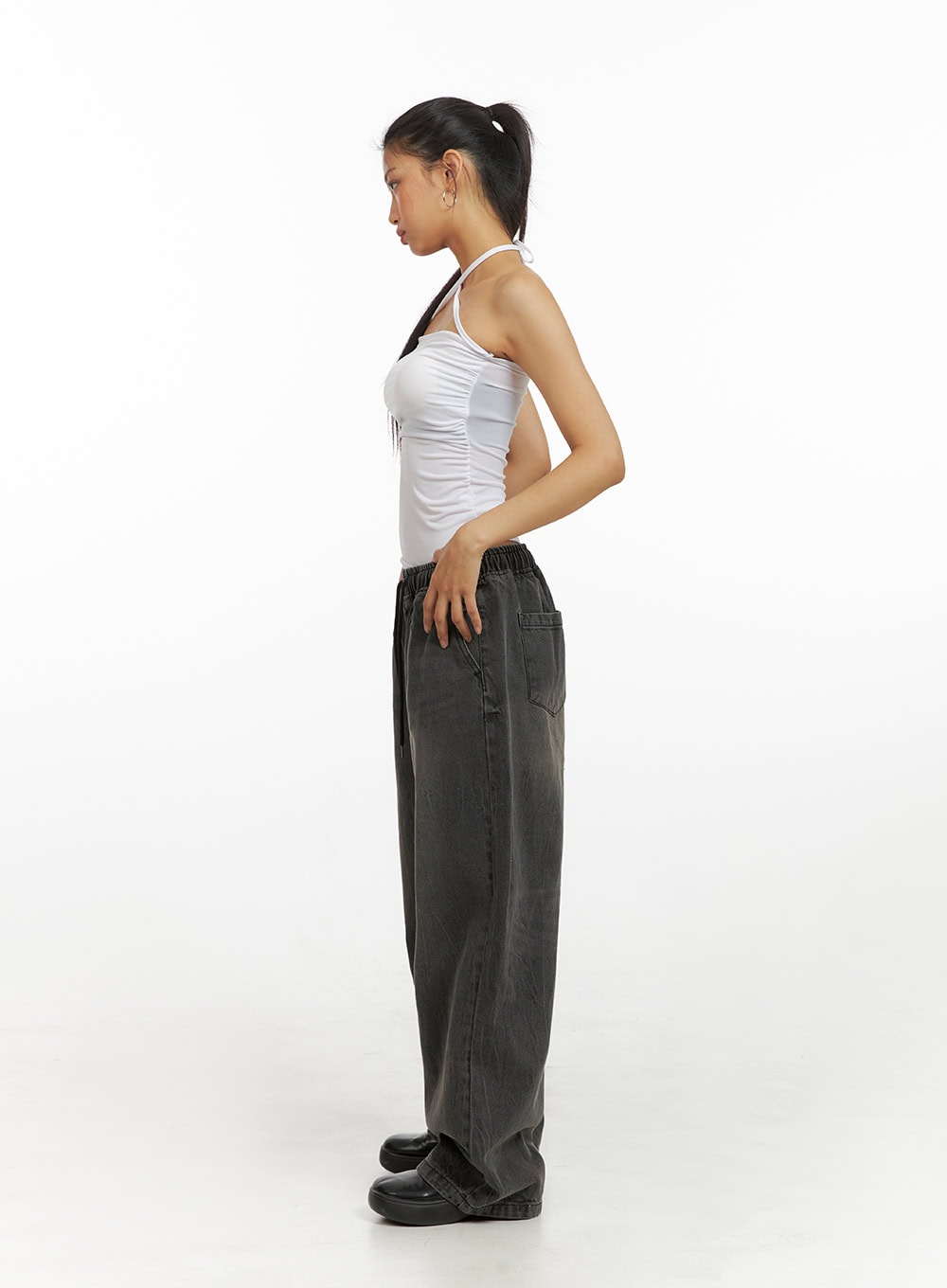 Banding Baggy Jeans IU412 in washed black, full-length side profile on model, wide-leg silhouette and floor-grazing hem highlighted, elastic waistband, paired with white halter top and black shoes.