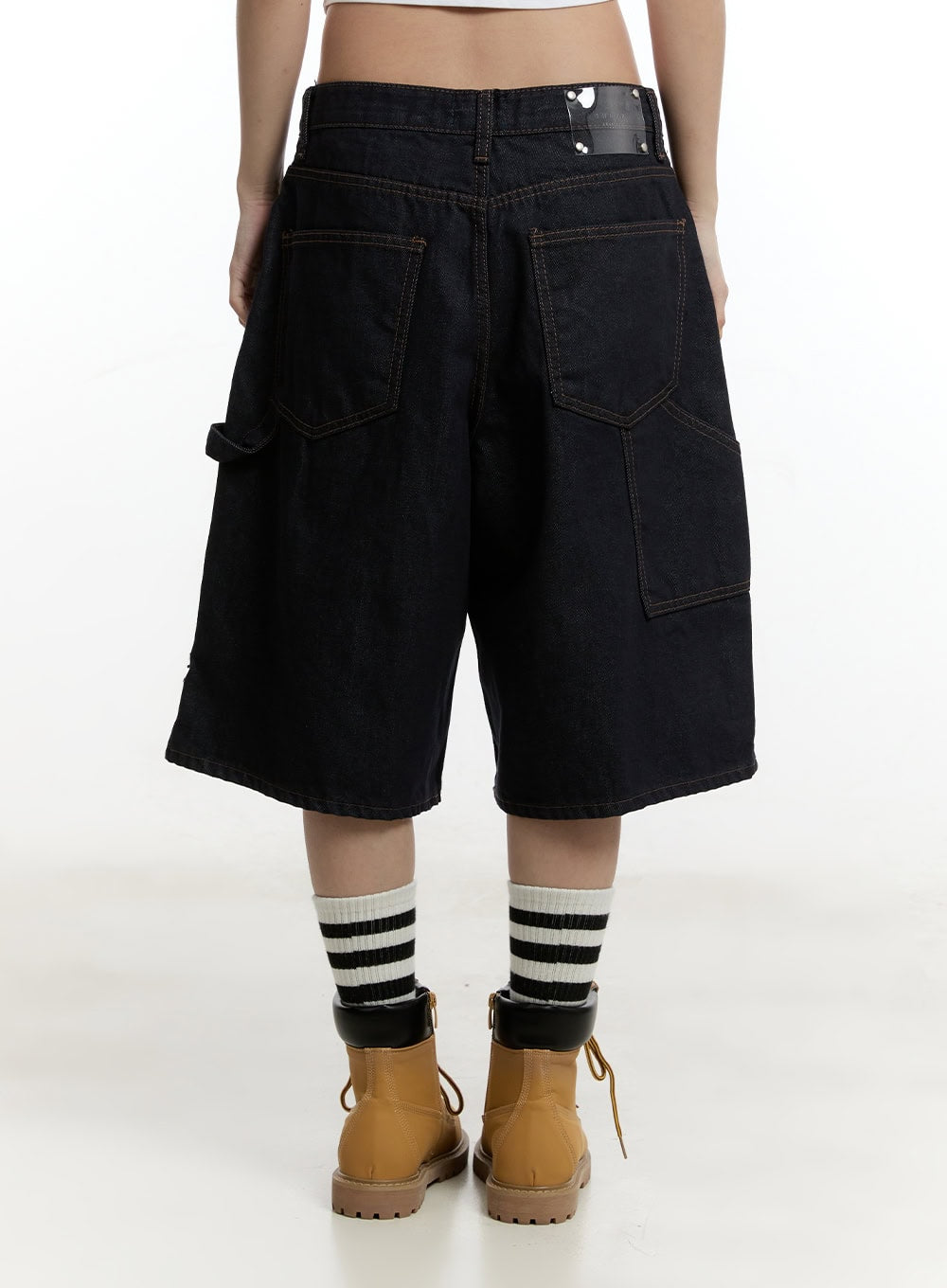 Carpenter Denim Wide-Leg Jorts CY501 in dark blue, back close-up on model, large utility patch pockets and contrast topstitching visible, low-rise waistband with brand label, striped socks and tan boots.