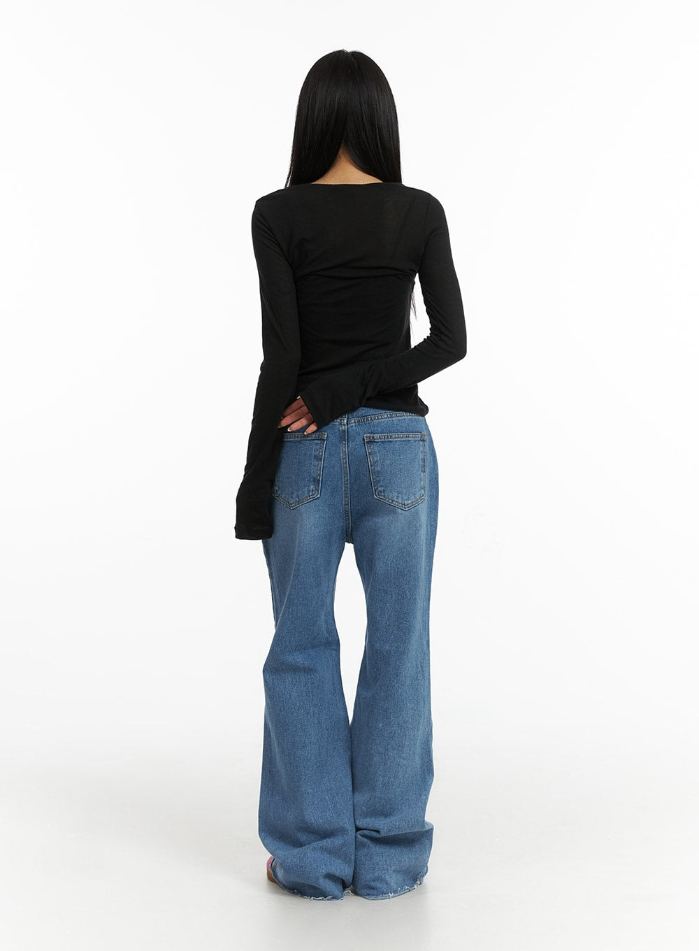 Blue Denim Bootcut Jeans CJ431 in blue, full-length back shot on model, showing two back patch pockets, wide bootcut flare with raw frayed hem, washed cotton denim, styled with black long sleeve top.