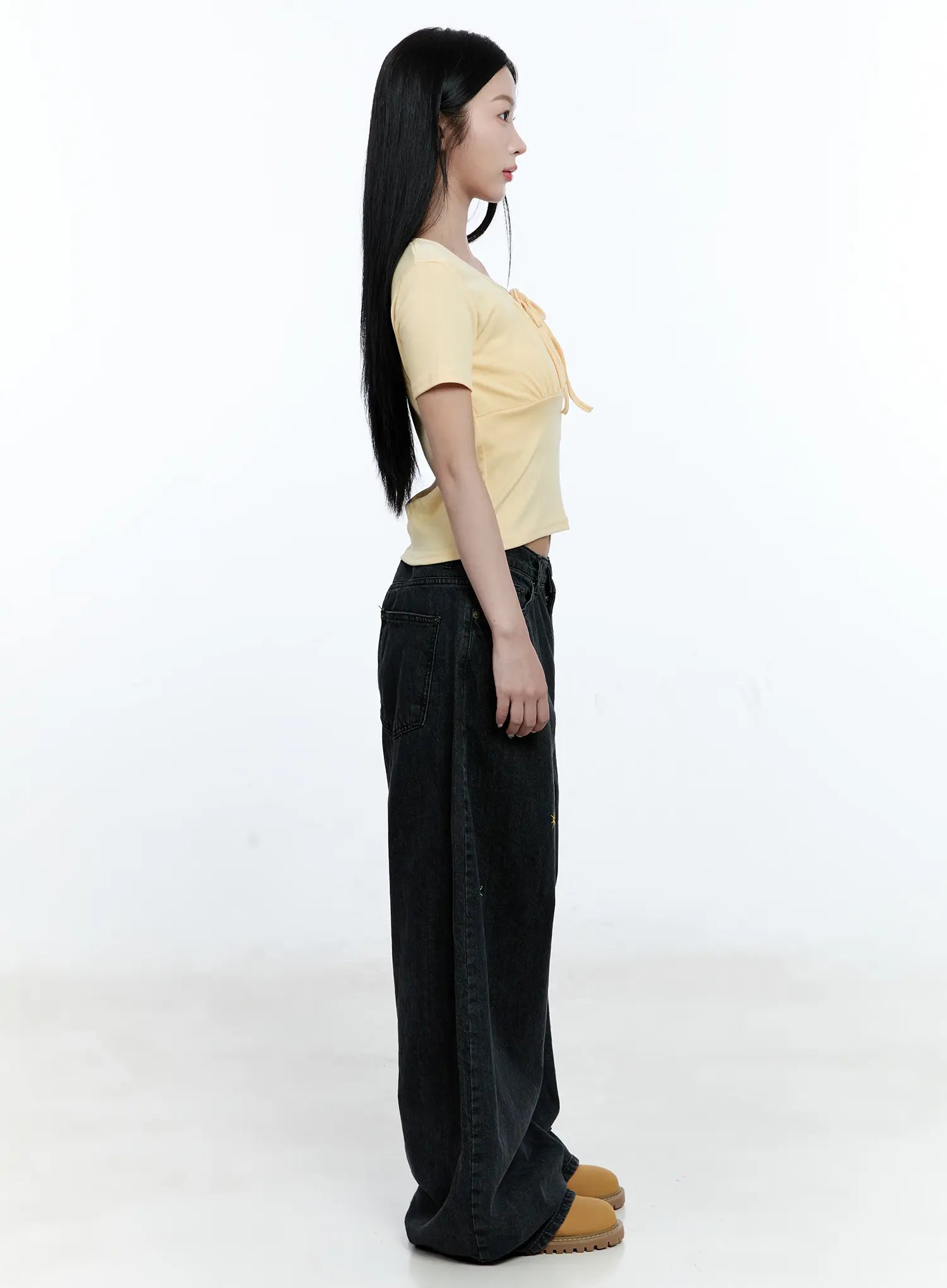 Wynter Star Embroidered Denim Jeans CG507 in black, full-length side profile on model, floor-grazing wide leg with slight pooling, styled with yellow crop top and tan platform shoes.