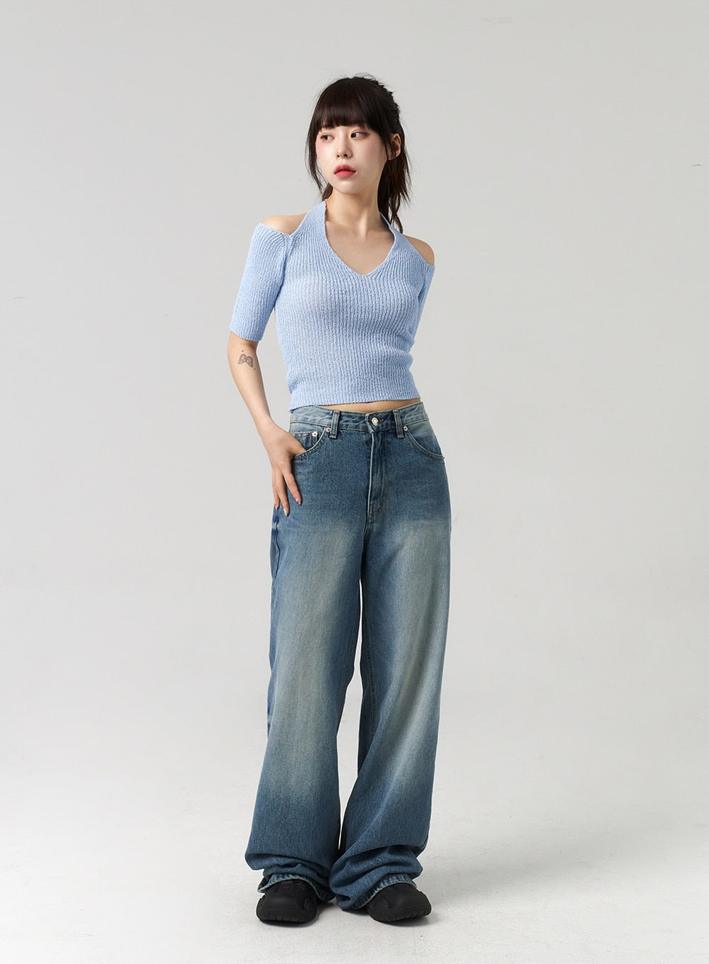 Mid-Wash Baggy Jeans CL312 in mid-wash blue, full-body slight angle on model hand in pocket, relaxed wide-fit denim with gradient mid-wash, paired with blue cold-shoulder knit.