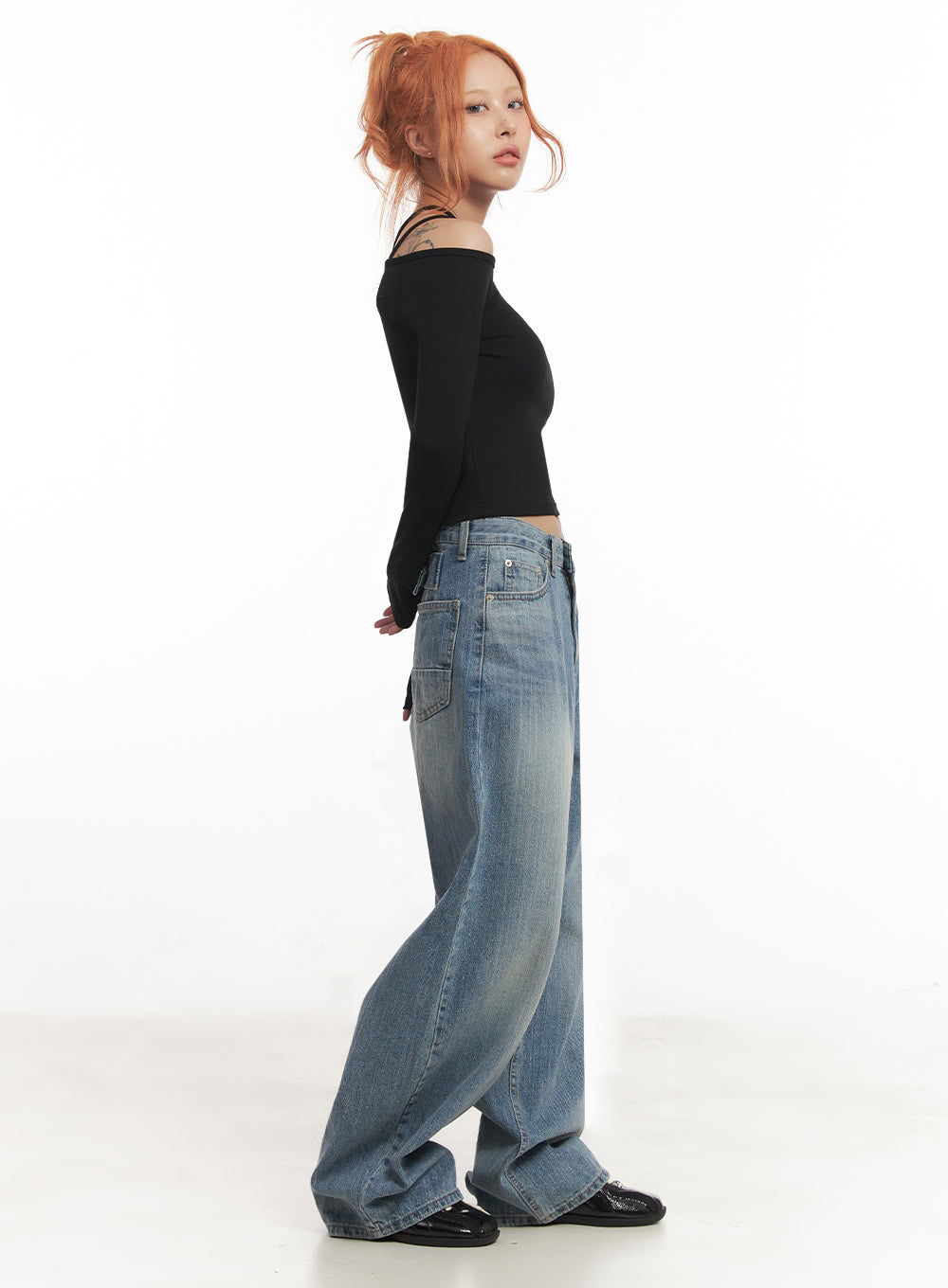 Yvette Washed Baggy Jeans IA517 in light blue, side view on model, exaggerated wide-leg silhouette with side seam detail and patch pocket, washed denim, styled with black off-shoulder top and black loafers.
