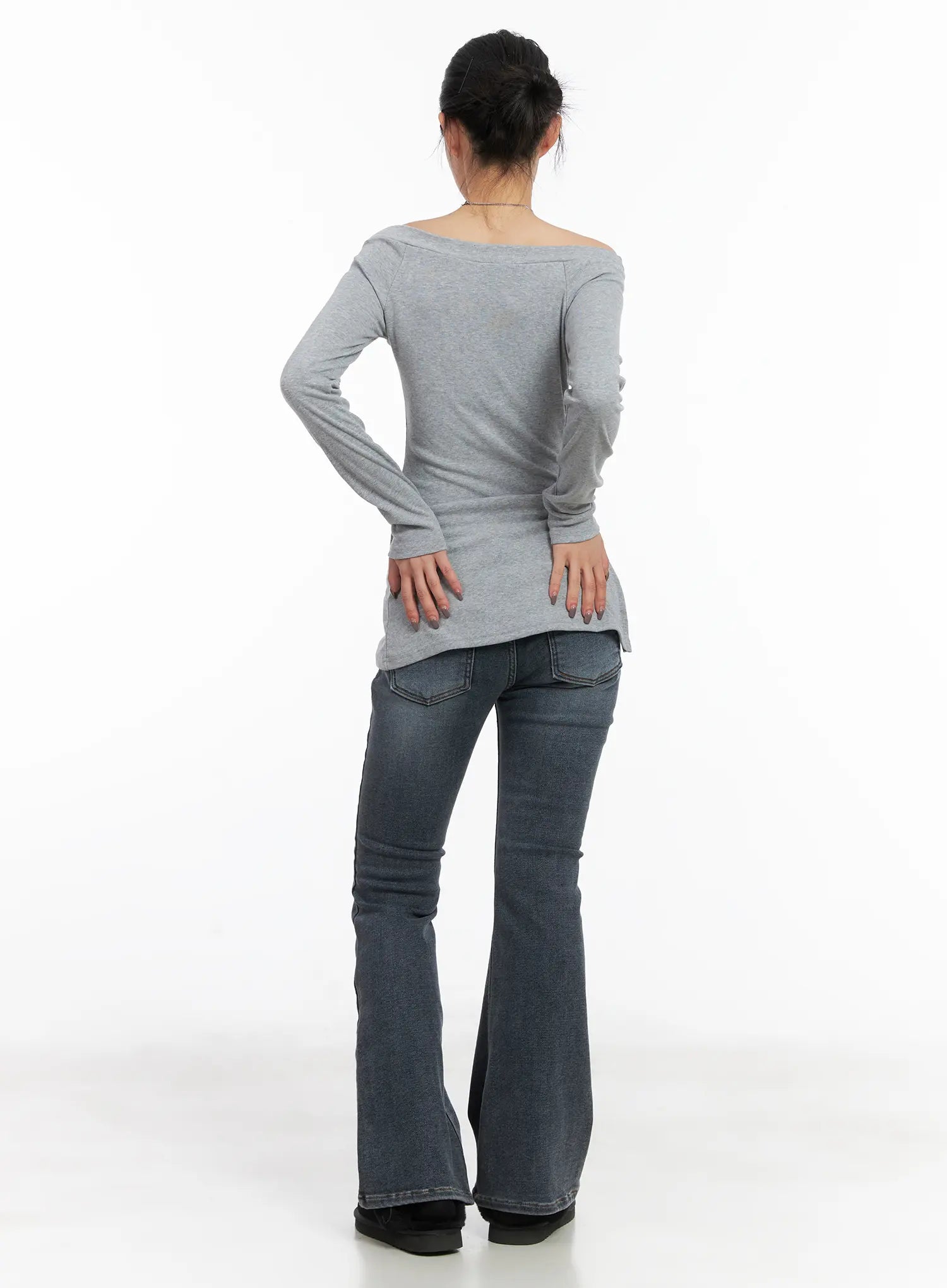 Kiera Low-Rise Fleece-Lined Bootcut Jeans CD509 in washed dark blue, full-body back view on model, bootcut flare silhouette, paired with grey off-shoulder long-sleeve top and black platform boots.