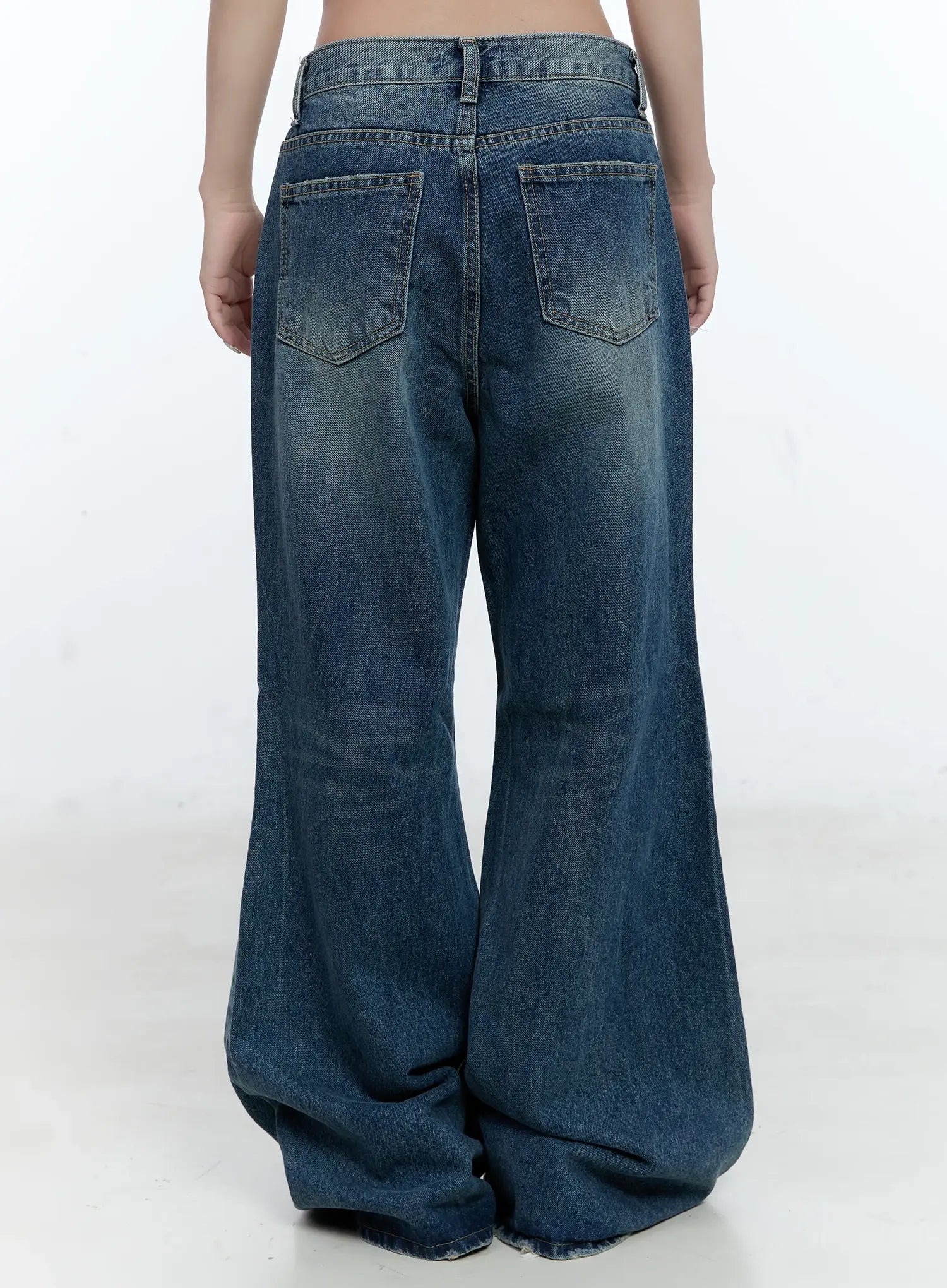 Gabi Distressed Semi-Flared Denim Jeans CG501 in dark blue, back view on model, showing dual back pockets, washed fade, wide semi-flared legs, and raw hem at floor.