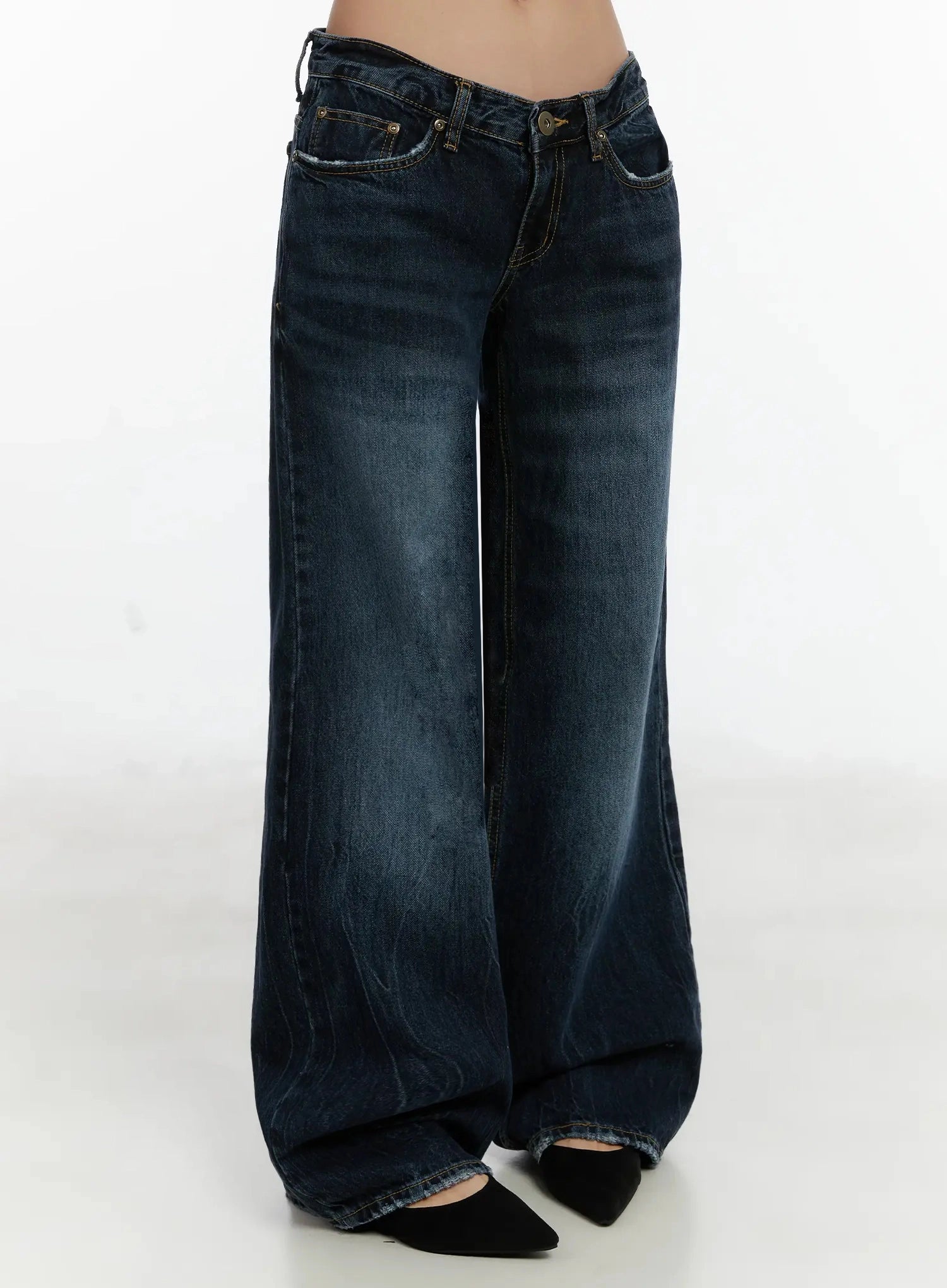 Aimee Low Rise Wide Leg Jeans ID525 in dark blue wash, three-quarter front-angle shot on model from waist down, wide leg silhouette with washed fading, low-rise waist and frayed hem detail.