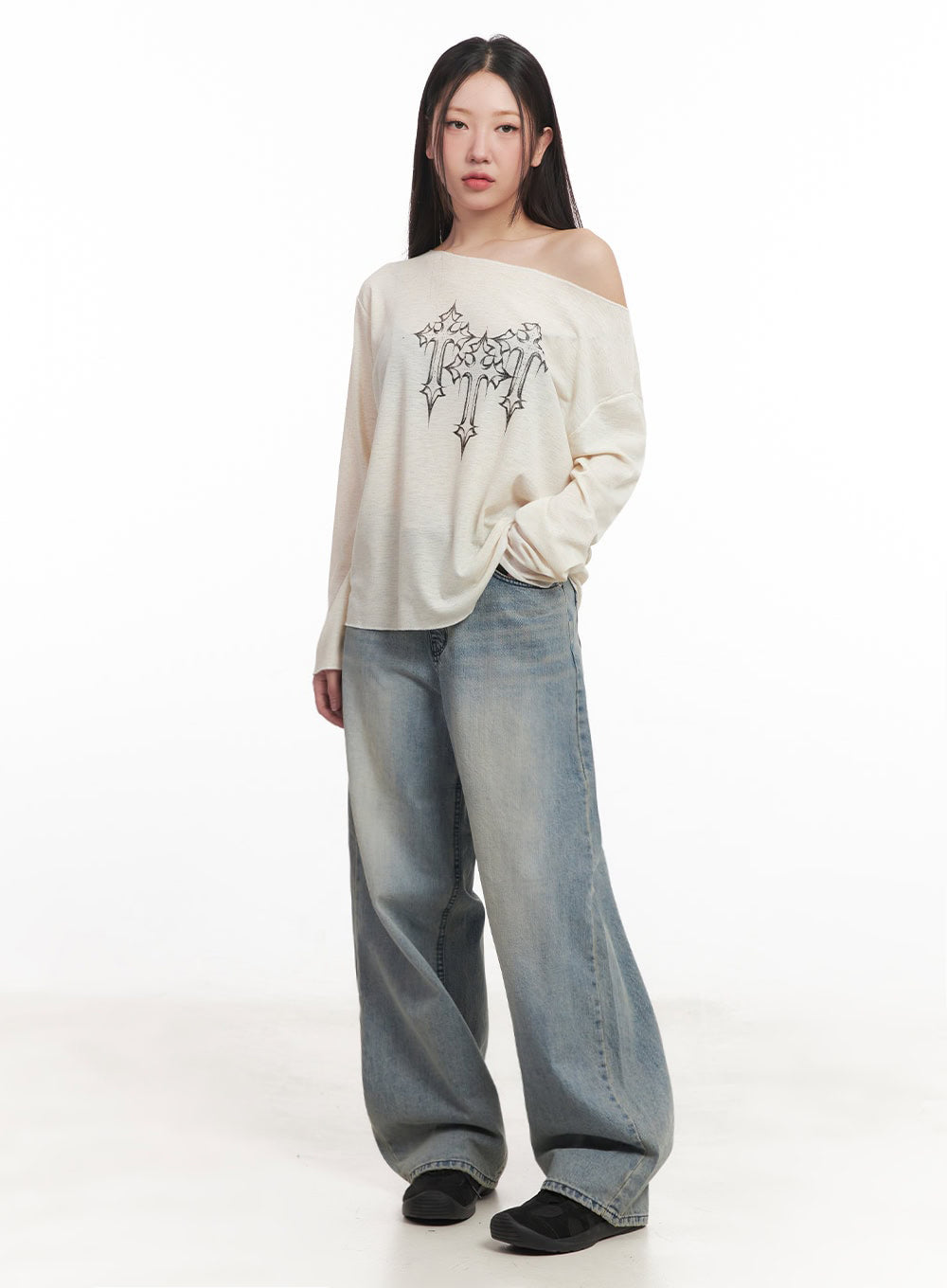 Casey Washed Baggy Jeans IM528 in light blue, full-length front on model, baggy washed denim with faded tones, wide pooling hem, paired with cream off-shoulder graphic knit top and black slip-on shoes.