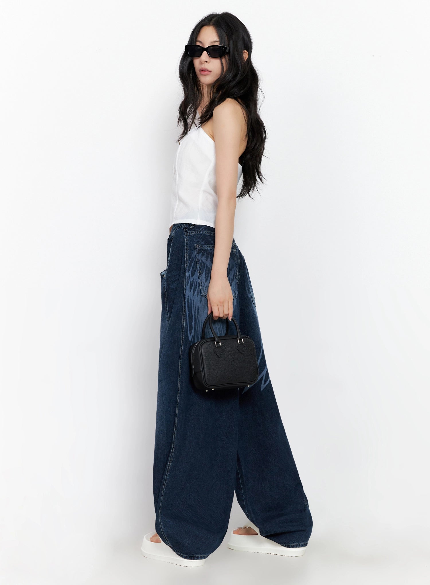 Sohee Angel Wing Print Wide-Leg Jeans IG508 in dark blue, side view on model, angel wing print visible on hip and leg, voluminous wide-leg silhouette, styled with white top and black mini bag.