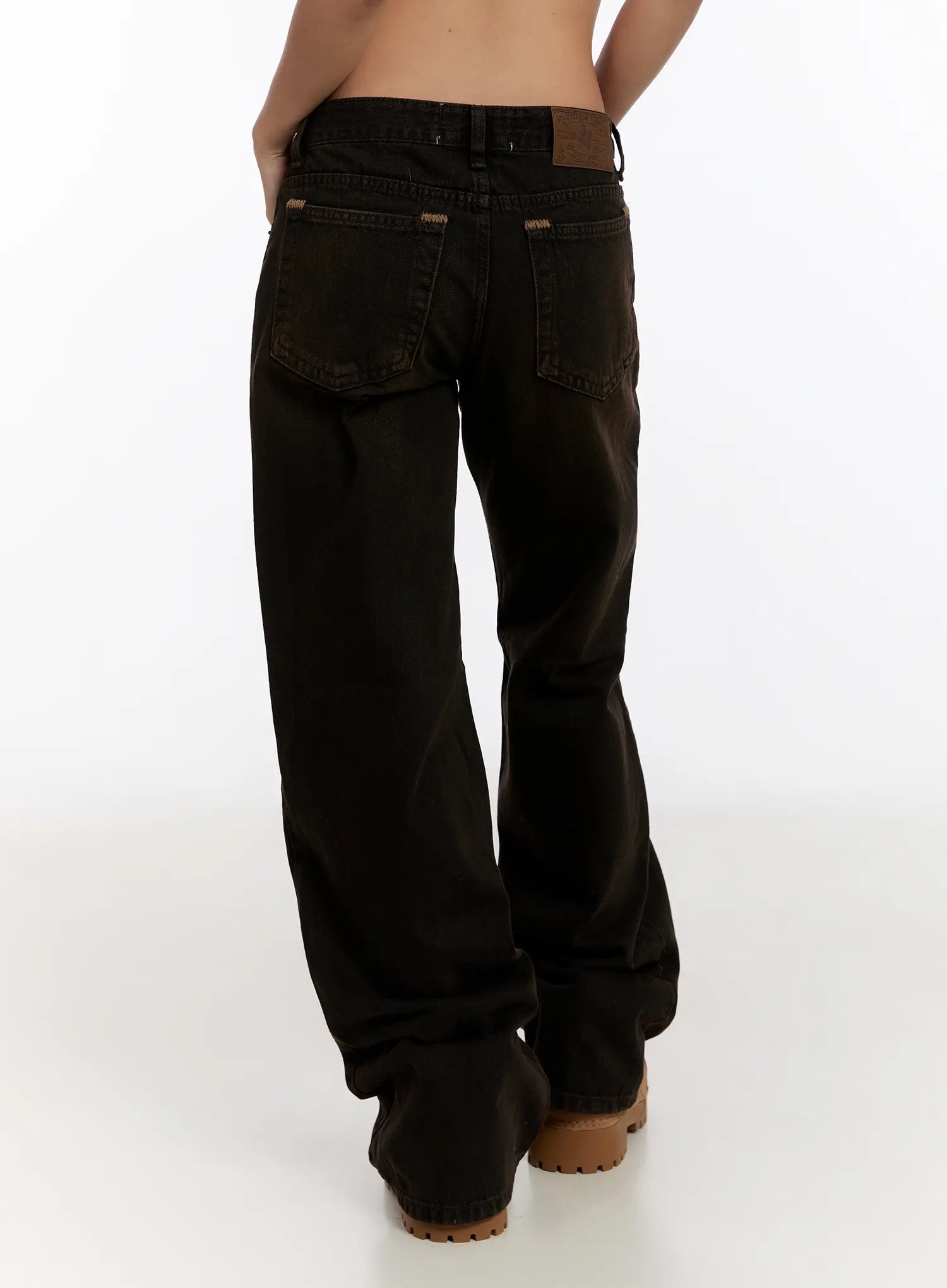 Mael Low Rise Straight Jeans CN527 in black, back view cropped on model, highlighting back pockets, leather logo patch, contrast caramel topstitching, and straight leg fall to floor.