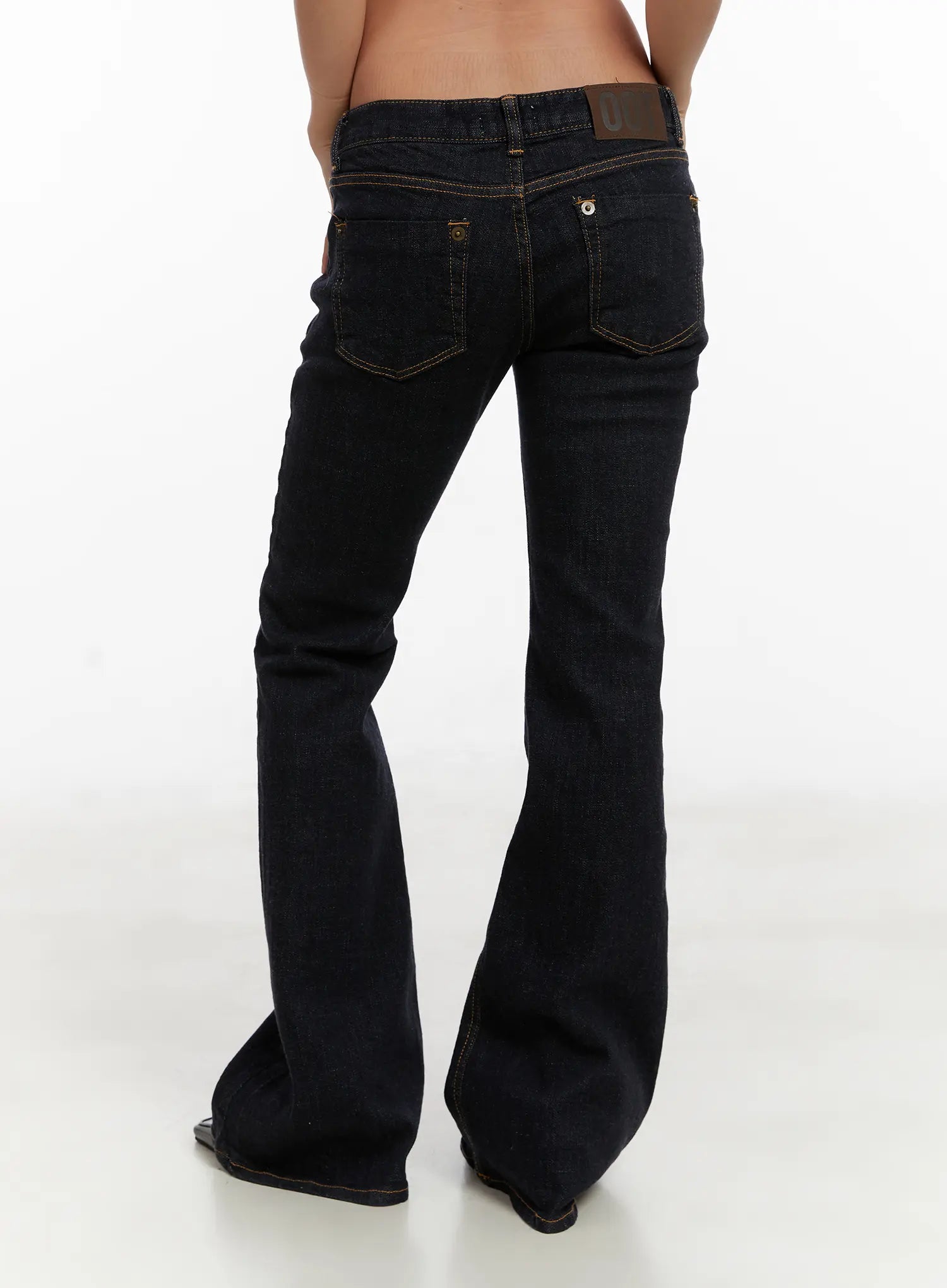 Adalee Non-Fade Low-Rise Flare Jeans CD515 in dark indigo, back product shot on model, full-length view of flare silhouette, back pockets with gold topstitching, and leather logo patch.