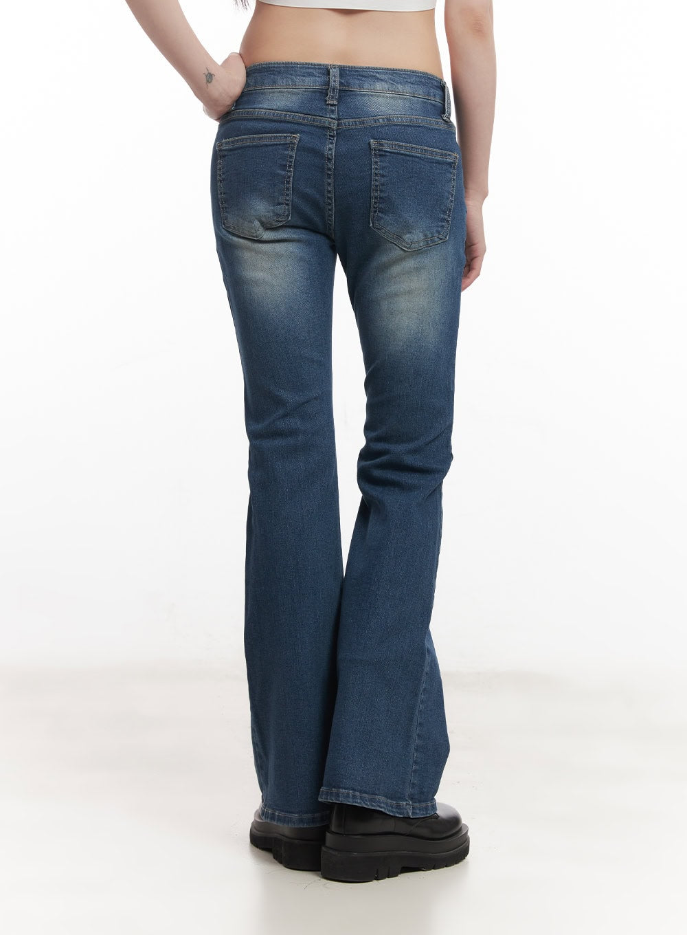 Rebecca Low-Waist Flared Jeans CM519 in dark blue, close-up back view on model, highlighting twin back pockets, washed denim, low waistband stitching, and flared leg opening.