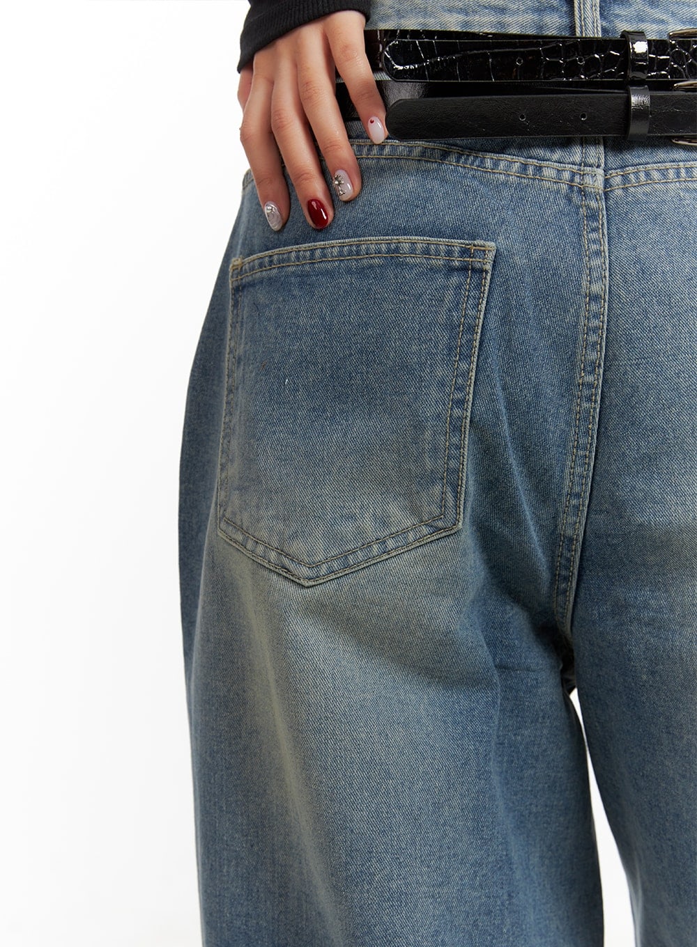 Washed Out Wide Fit Baggy Jeans CA416 in blue, back pocket close-up on model, stitched patch pocket on faded washed denim, croc-texture black belt at waist.