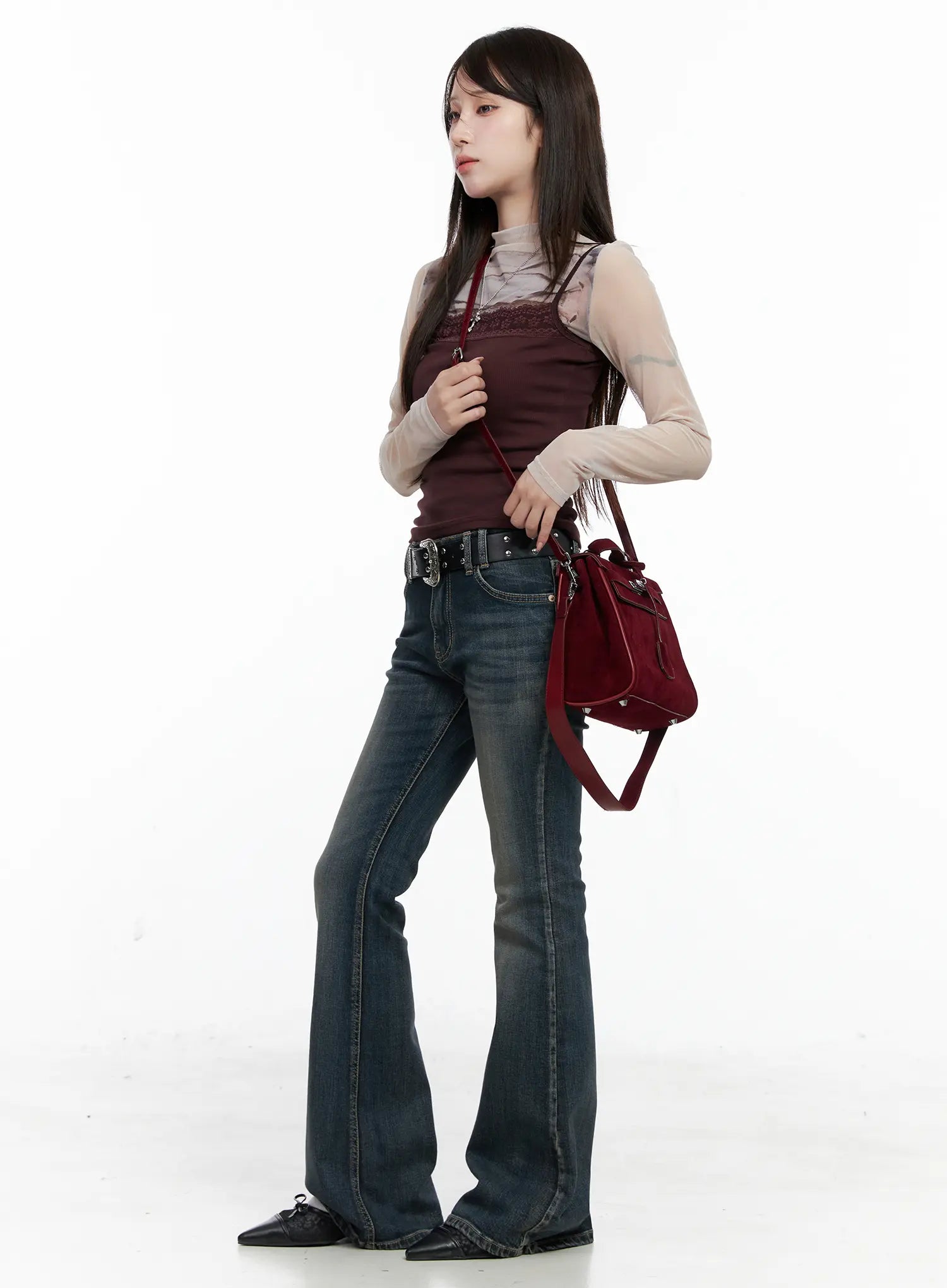 Rosé Washed Bootcut Jeans CO520 in dark blue, three-quarter side editorial shot on model, styled with layered mesh top, burgundy cami, belt, and red suede crossbody bag.
