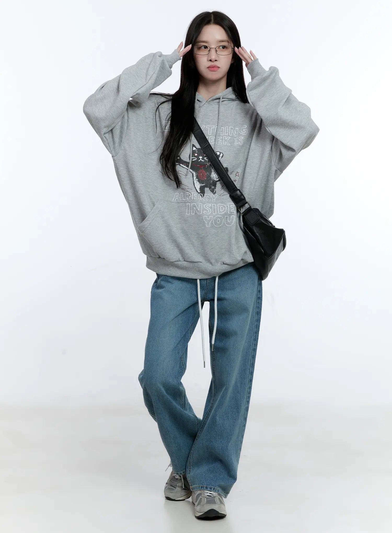 High-Waist Wide-Leg Drawstring Jeans CG513 in blue, full-body front shot on model, wide-leg washed denim with white drawstring, styled with grey graphic hoodie, glasses, and black crossbody bag.