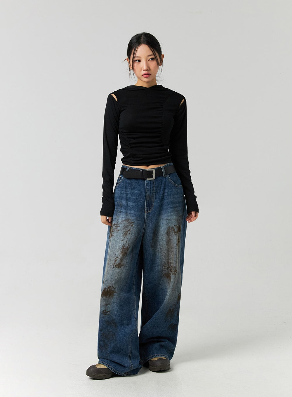 Street-Style Wide Fit Washed Jeans CO323 in Blue, full-body front on model in black cut-out long-sleeve top and belt, wide fit washed denim with brown abstract stain pattern, floor-grazing length.