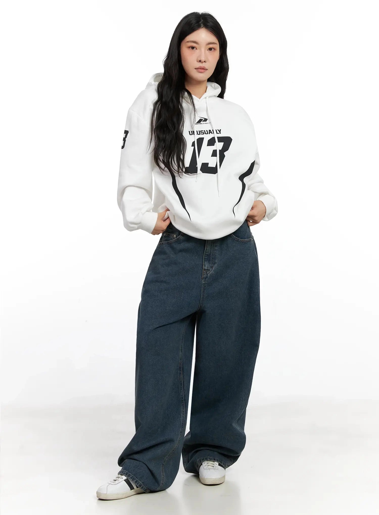 Aleena Mid-Wash Baggy Jeans IN528 in dark blue, full-length front shot on model styled with white graphic hoodie, casual streetwear look with wide-leg silhouette and white sneakers.