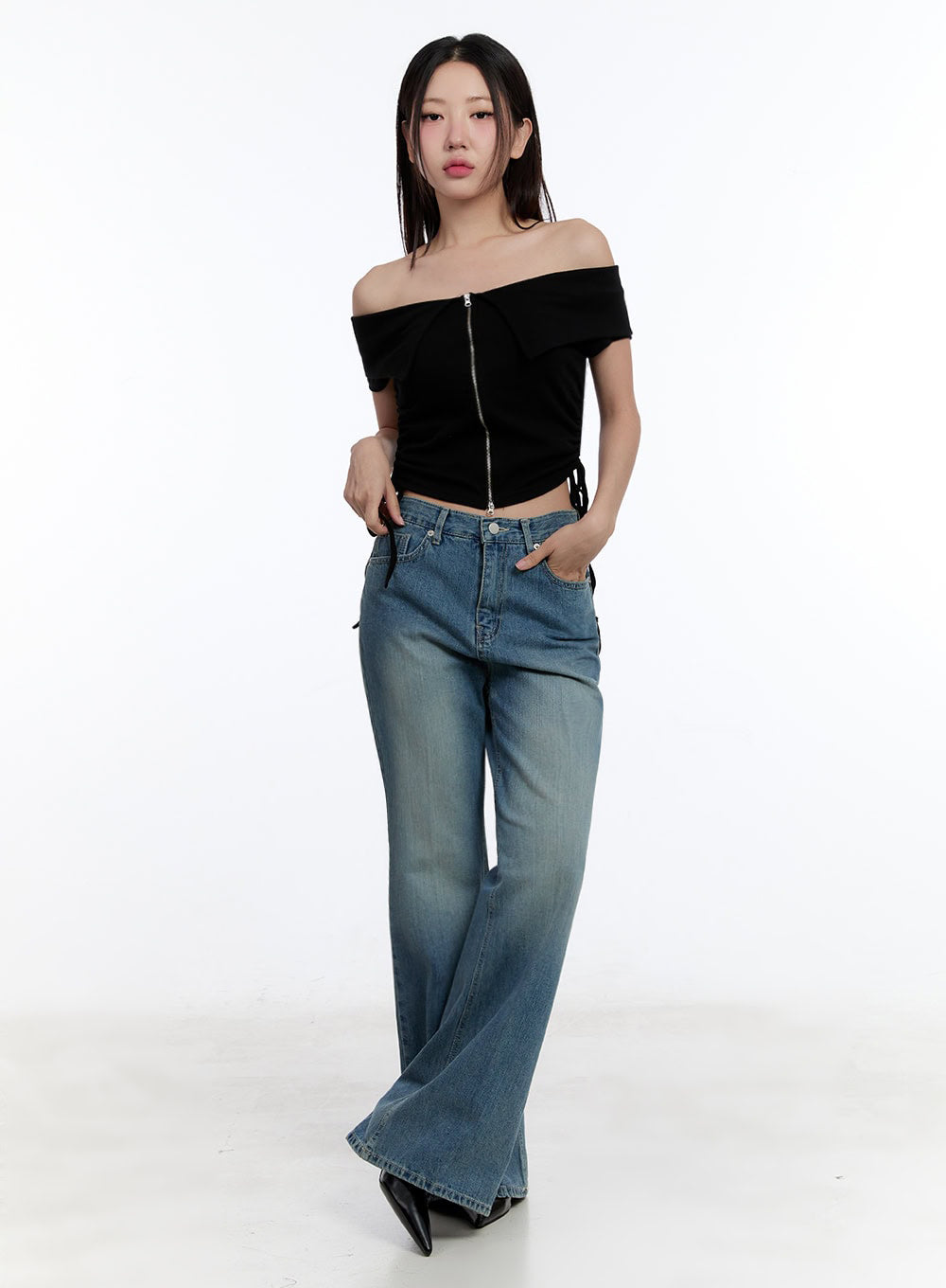 Aliya Washed Bootcut Jeans IU503 in dark blue, three-quarter front shot on model in motion, wide-fit washed denim with bootcut hem, styled with black off-shoulder crop top.