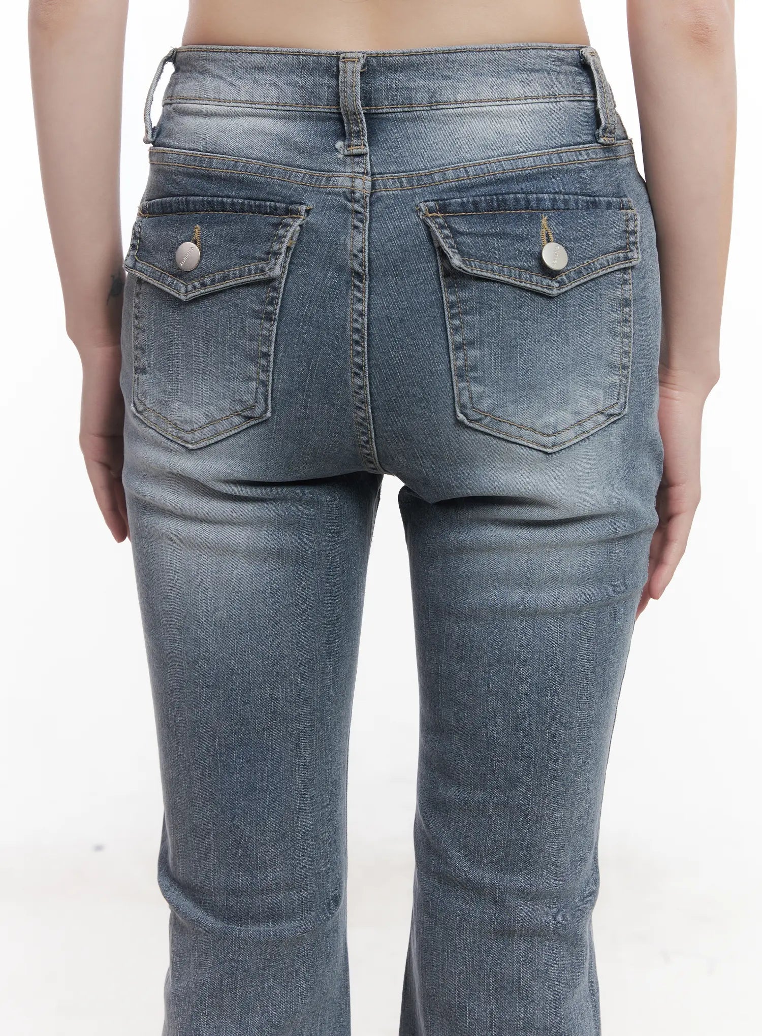 Soyeon Flared Jeans with Hip Pads CU520 in dark gray, back close-up on model from waist to mid-thigh, dual snap-button rear pockets with washed denim texture and hip-pad shaping visible.