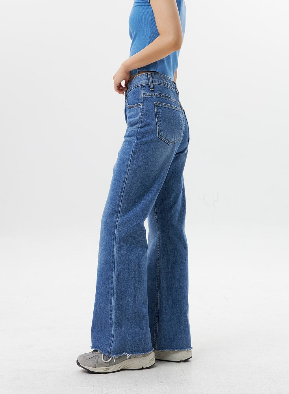 Straight-Leg Jeans OG318 in medium blue, side-rear close-up on model, highlighting back pocket stitching, high-rise waistband, straight-leg silhouette with raw frayed hem, worn with blue crop top.
