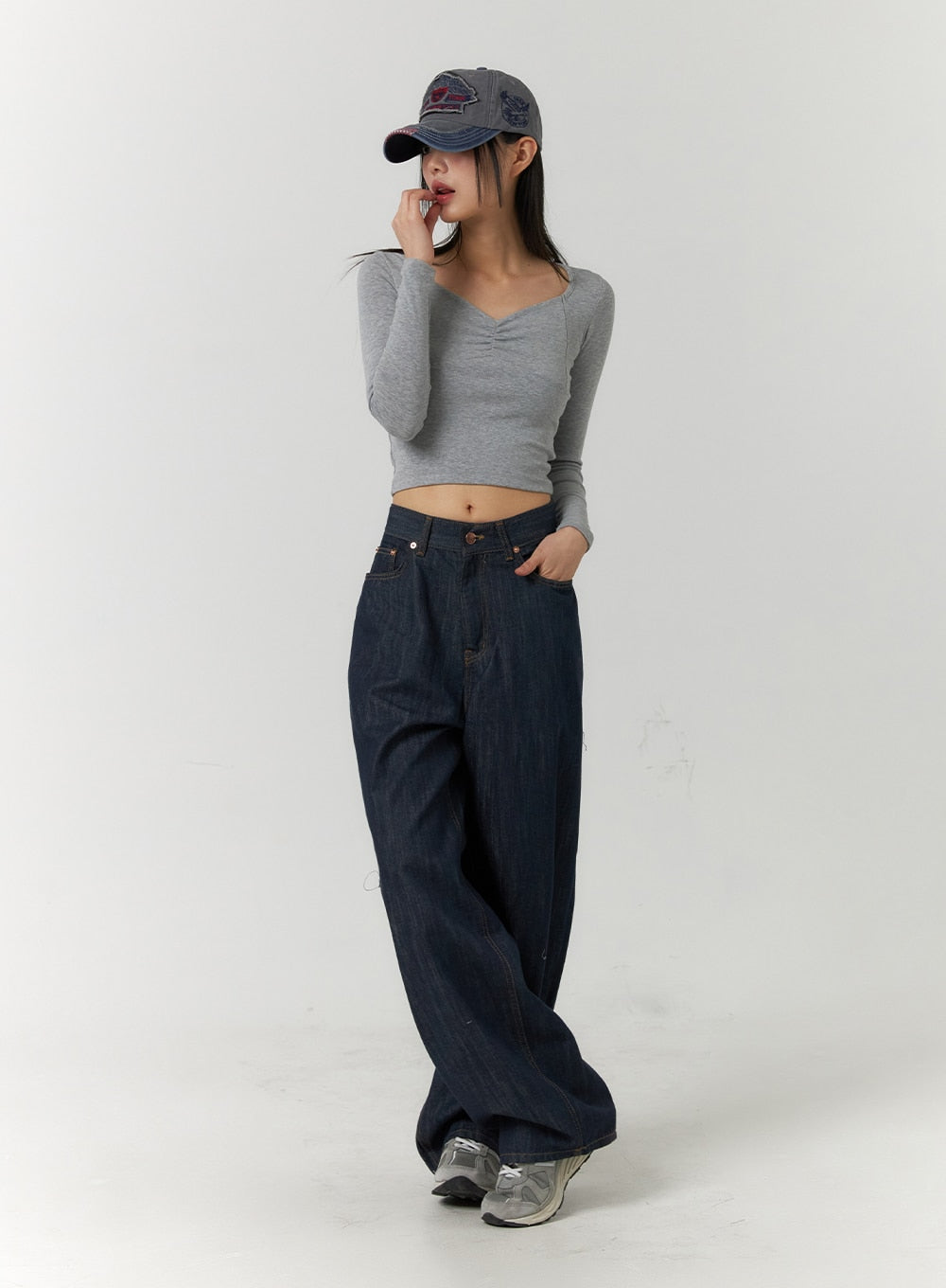 Back Button Wide Leg Jeans CF407 in blue, full-body front angled view on model, relaxed wide-leg dark denim with copper-tone hardware, paired with grey crop top and denim cap.