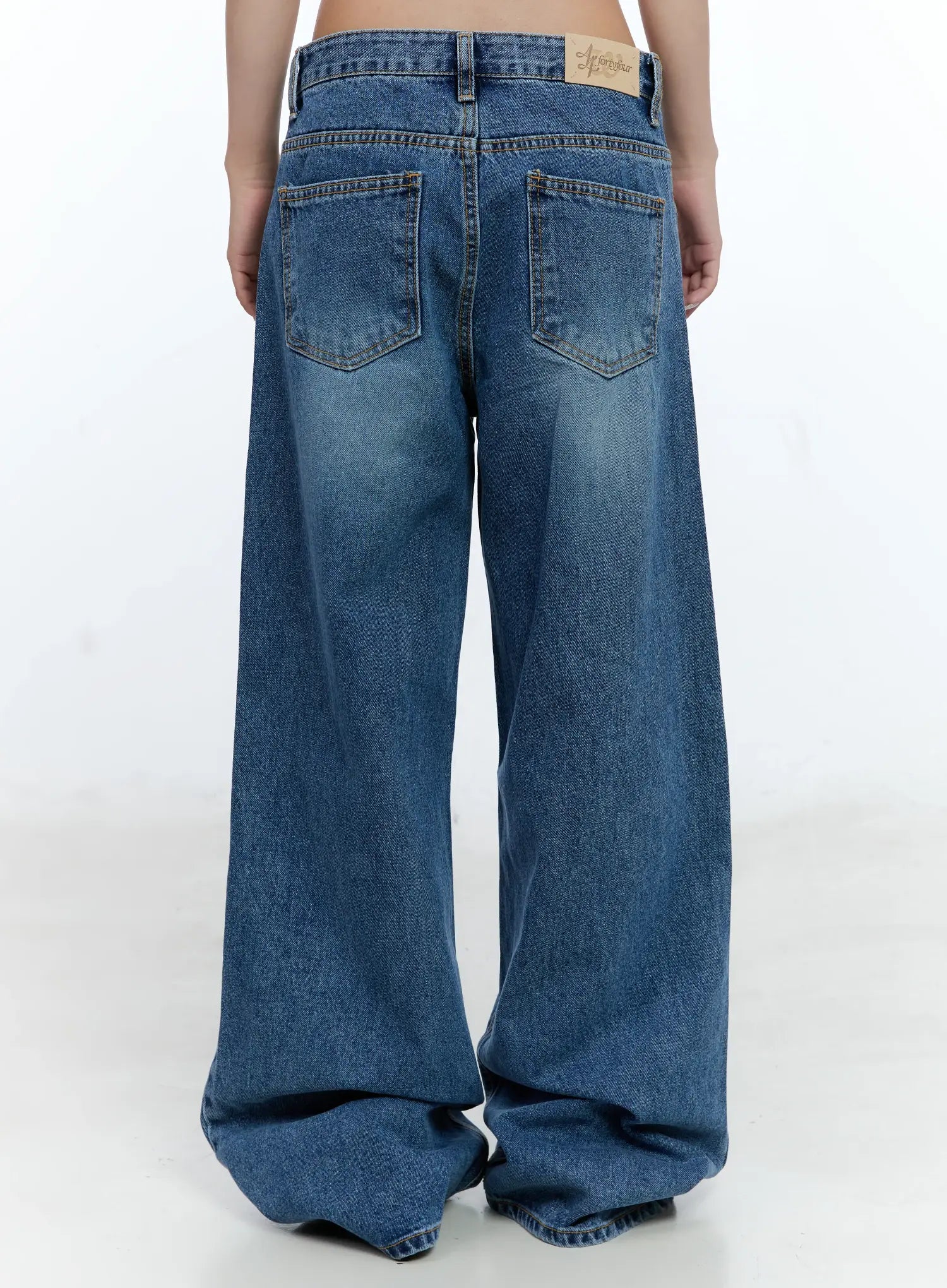 Dahye Washed Relaxed-Fit Denim Jeans CL530 in blue, back close-up on model, dual back pockets with gold contrast stitching, branded label patch at waistband, washed relaxed-fit denim.