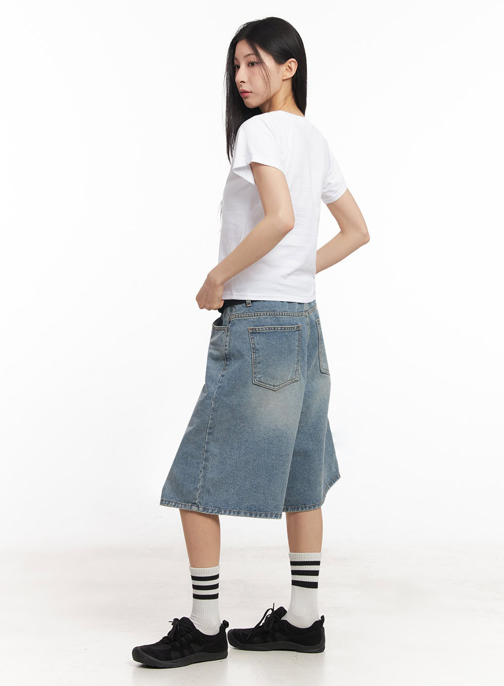 Washed Baggy Jorts IY529 in light blue, back three-quarter side shot on model, wide midi washed denim with back patch pockets and faded details, paired with white crop tee and black sneakers.