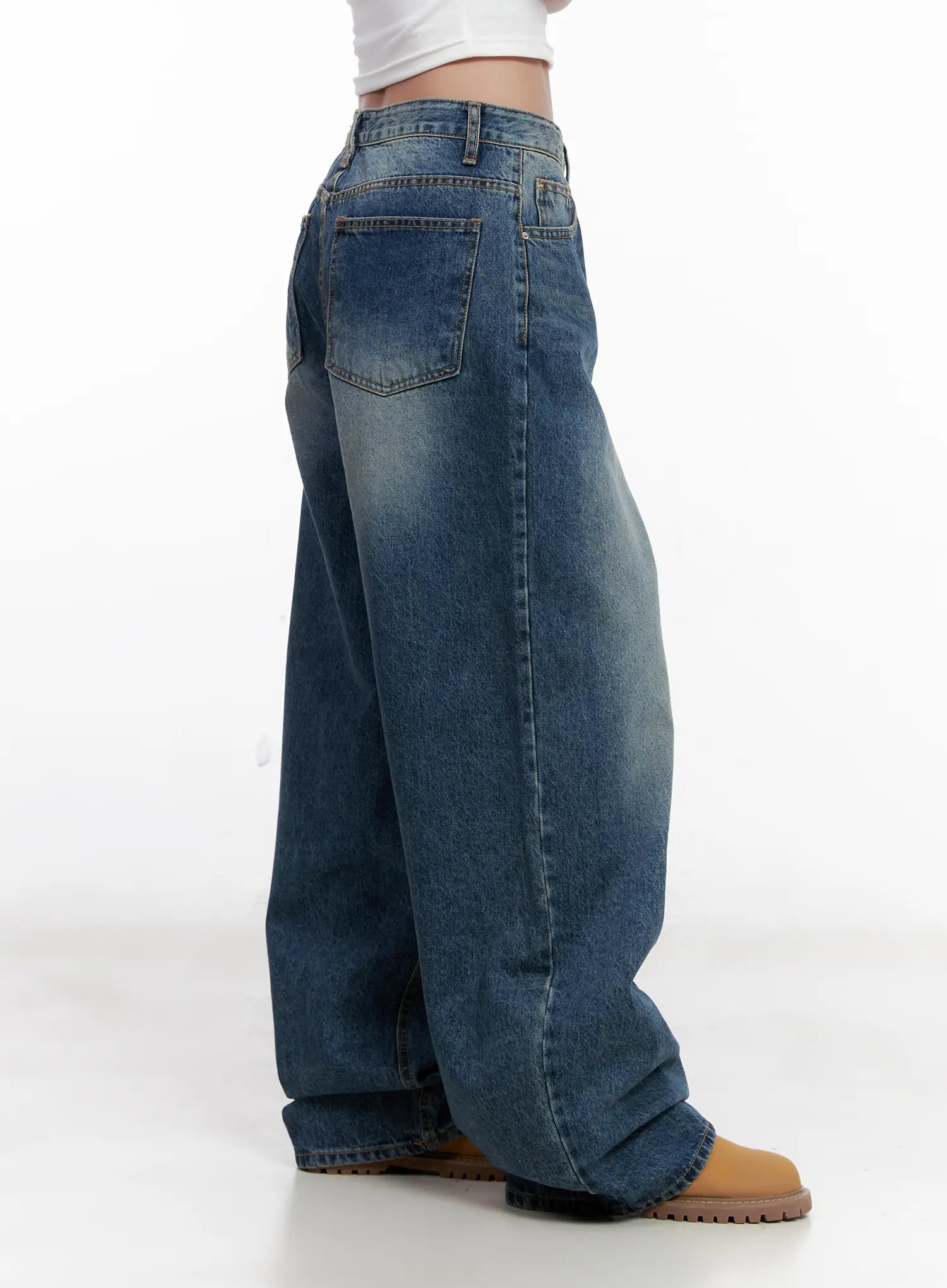 Miji Wide-Leg Washed Denim Jeans CL521 in dark blue, rear-side close-up on model, back pocket detail with topstitching, washed denim texture visible, hem pooling over tan chunky boots.