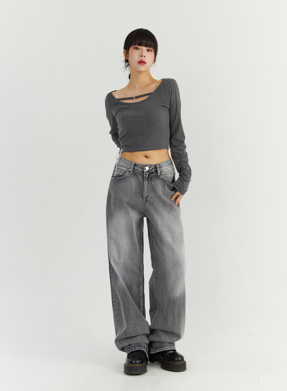 Grey Washed Wide Leg Jeans CO323 in Gray, full-body front view on model with hand in pocket, wide-fit washed cotton denim in darker gray tone, paired with cut-out crop top and platform boots.