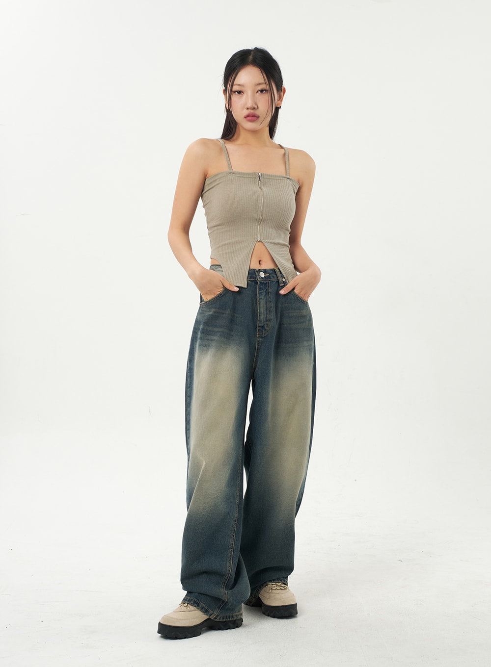 Mid-Rise Baggy Jeans CA325 in vintage blue denim, full-length front view on model with hands in pockets, wide baggy leg with yellow-fade wash, paired with beige ribbed cami top and chunky boots.