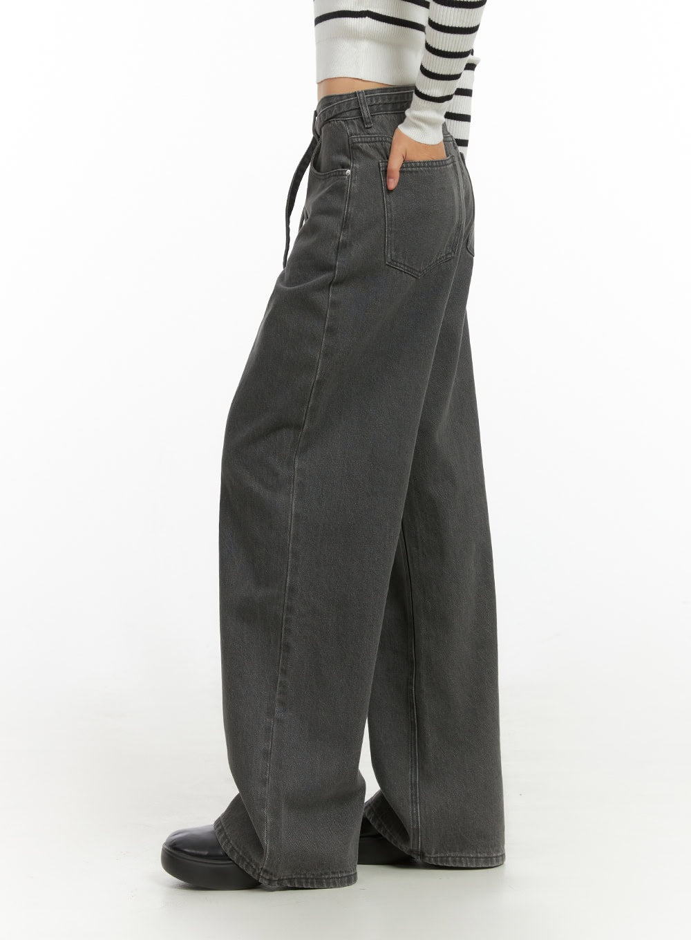 Emery Cotton Strap Baggy Jeans IO409 in dark gray, side view on model, showing wide-leg silhouette and strap detail at waist, worn with striped crop top.