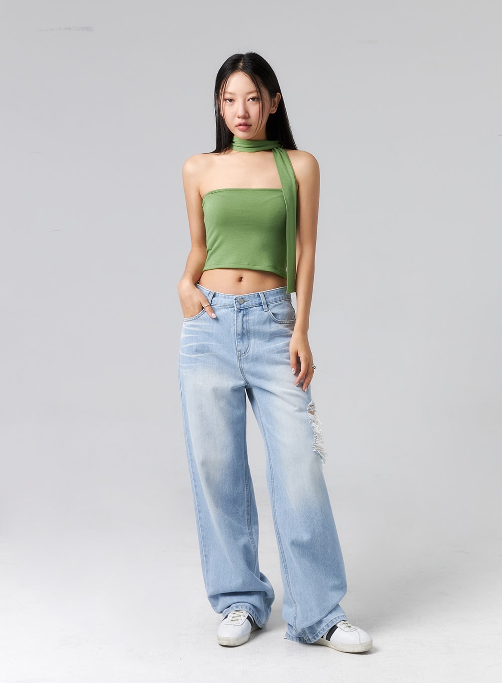 Ripped Side Jeans CL320 in light blue, full-length front shot on model with hand in pocket, wide-fit street-style denim with side destroyed detail at thigh, styled with green halter top and white sneakers.