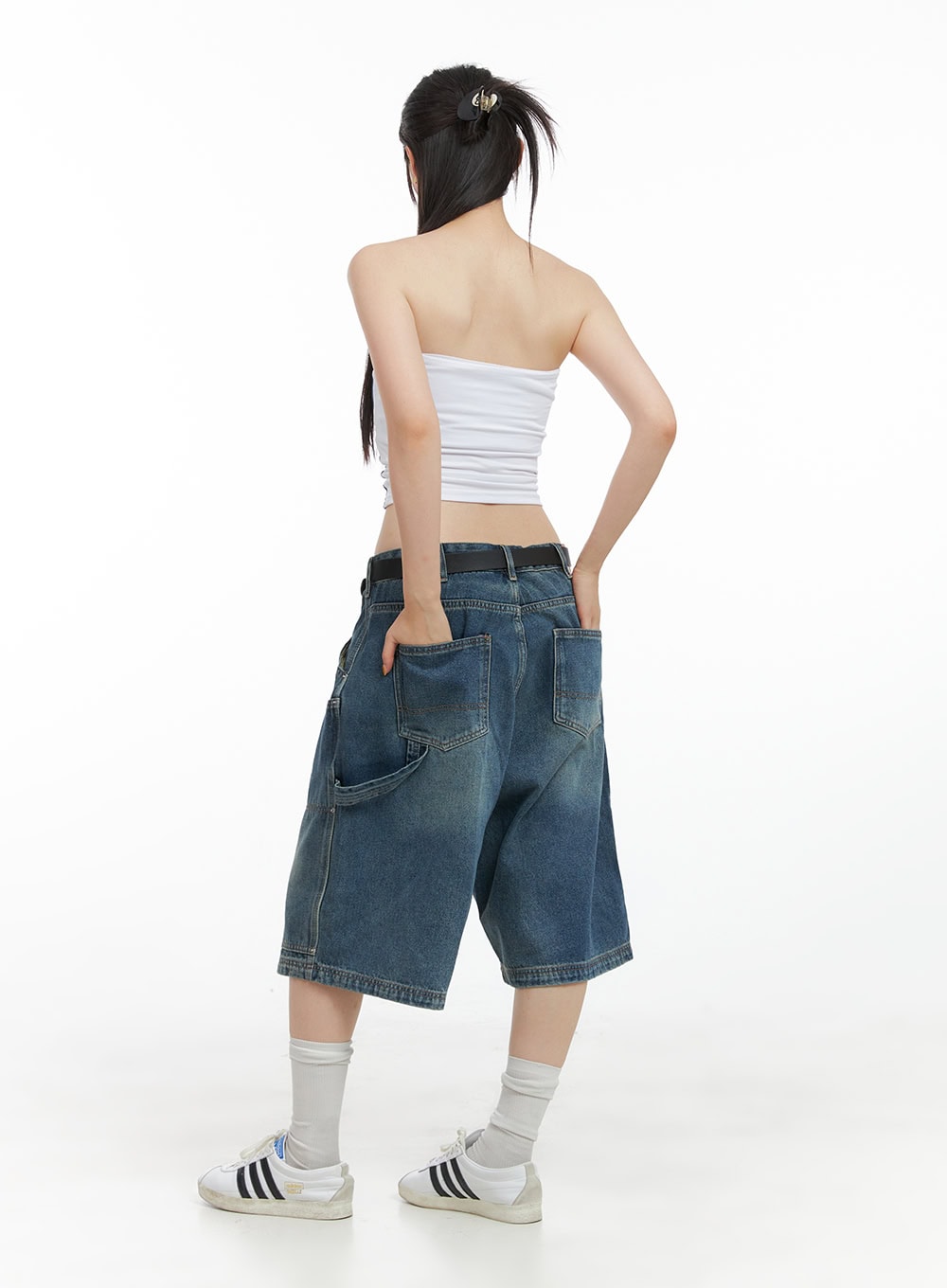 Stud Washed Baggy Jorts (UNISEX) CG408 in blue, full-body back on model, wide-fit washed denim jorts with oversized back pockets, belted waist, styled with white bandeau top and sneakers.