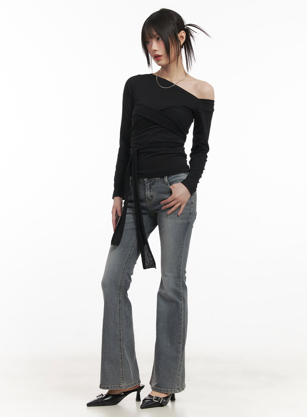 Rachel Washed Bootcut Jeans with Hip Pads CF518 in gray, three-quarter front editorial shot on model, low-waist bootcut flare denim with hip pad detail, paired with black asymmetric top.