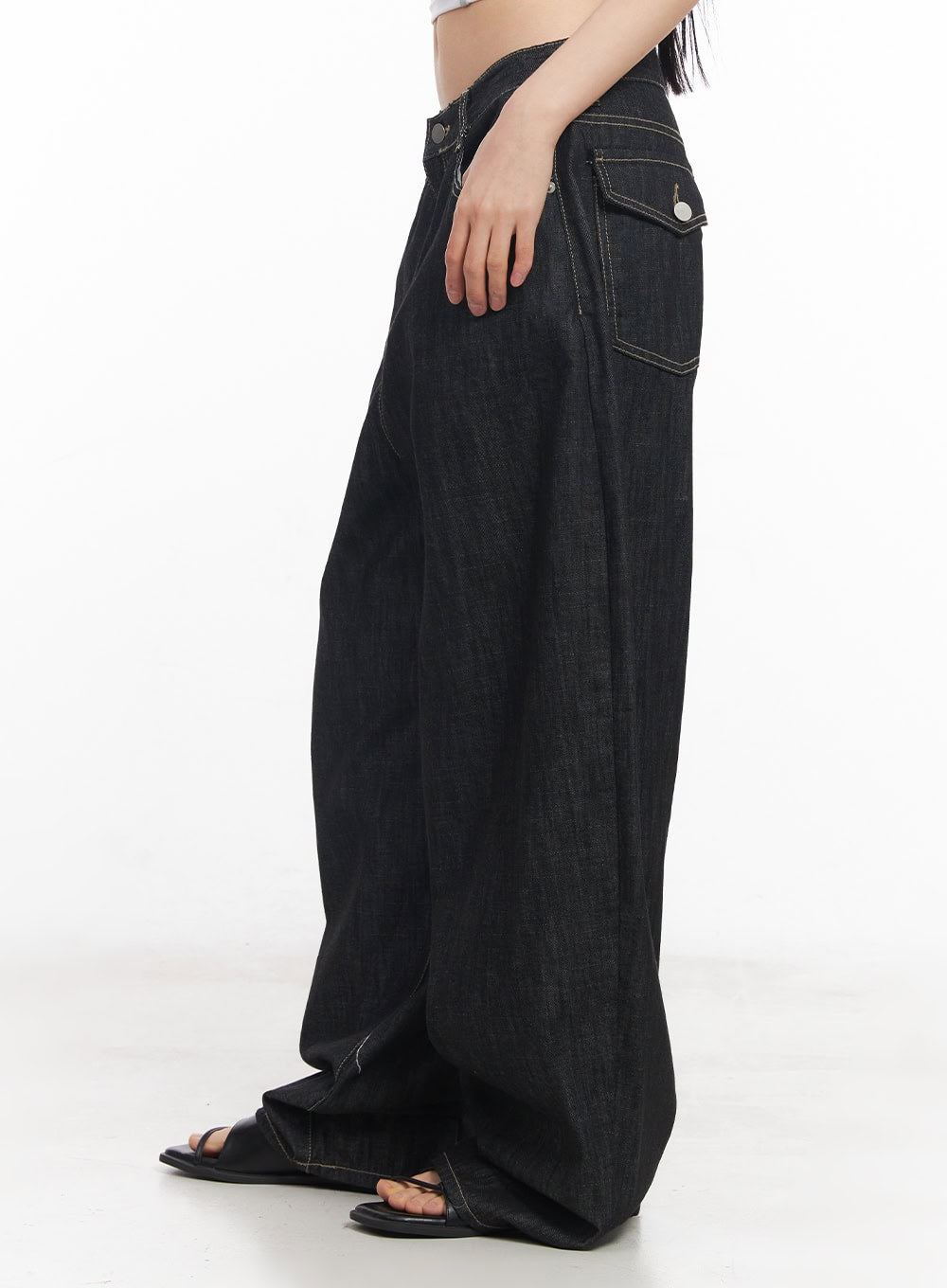 Elvie Baggy Jeans CY528 in black, side close-up on model, showing back coin pocket with silver button detail and contrast stitching on raw-finish denim.